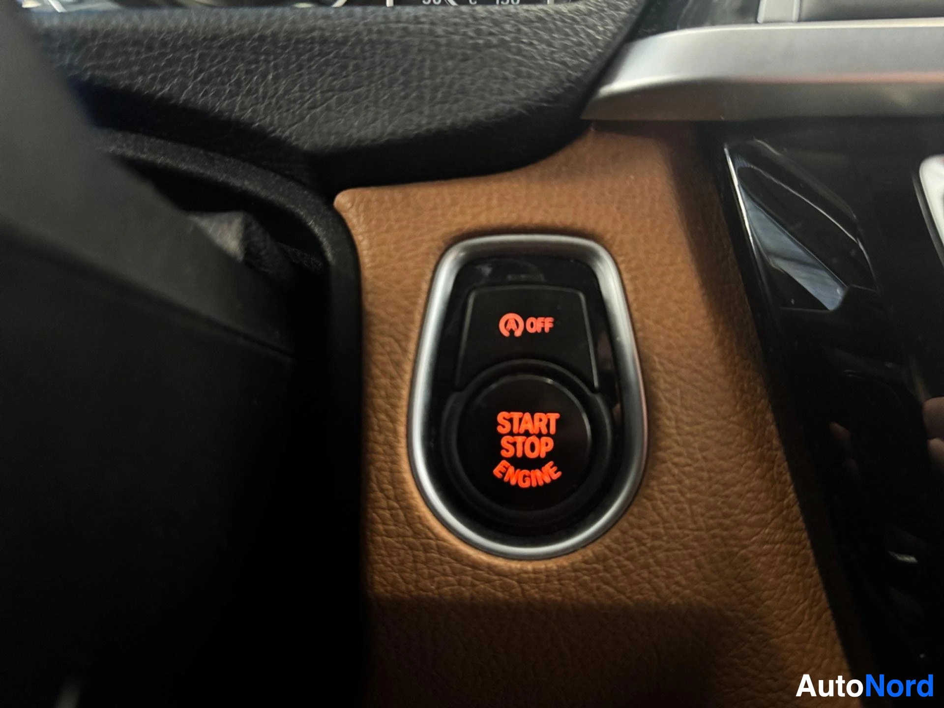 Engine start-stop button on leather-wrapped steering wheel