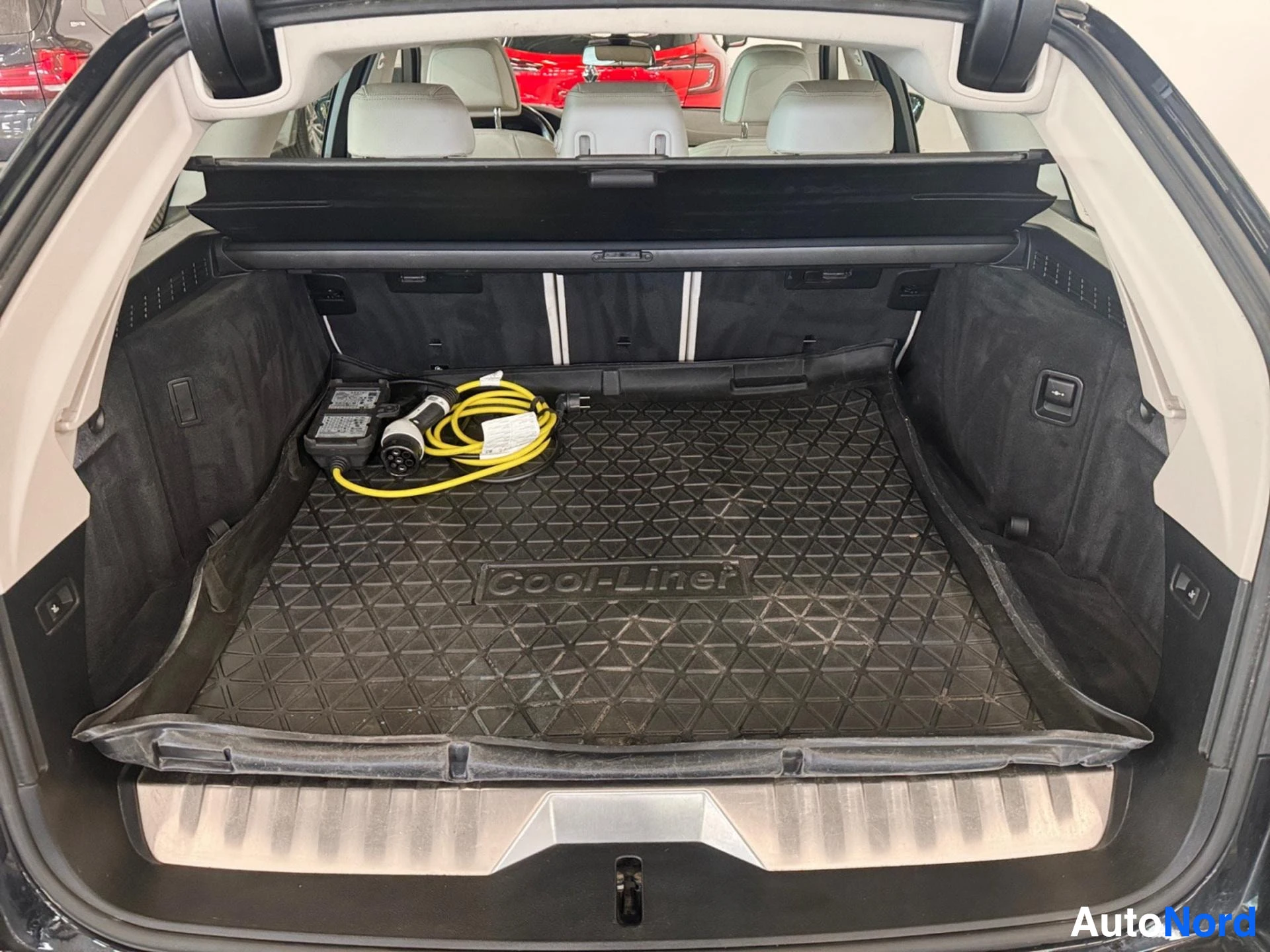 Open trunk interior showing black rubber mat and charging cable inside