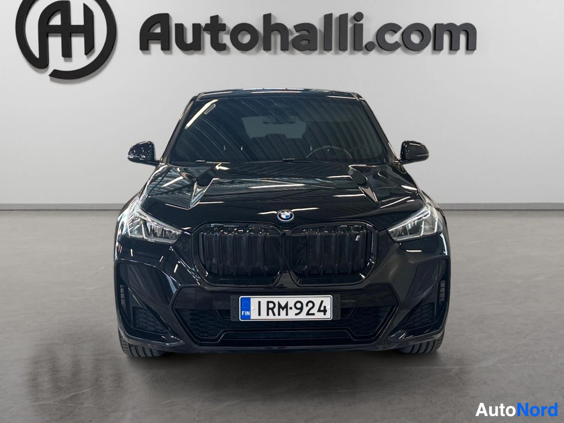 Musta BMW iX1 suorasta edestä, sähköauto sulokkein grillillä
