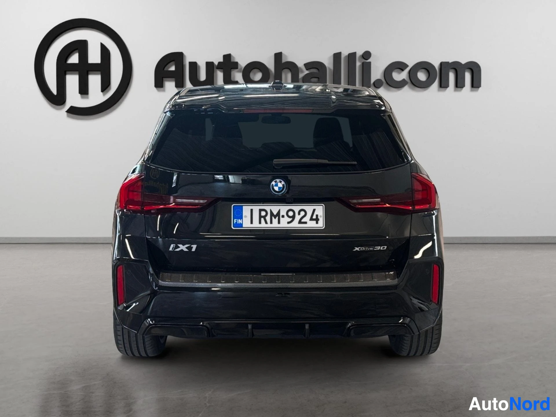 Musta BMW xDrive nelivetoiskulmasuv, takanäkymä punaisilla takavaloilla