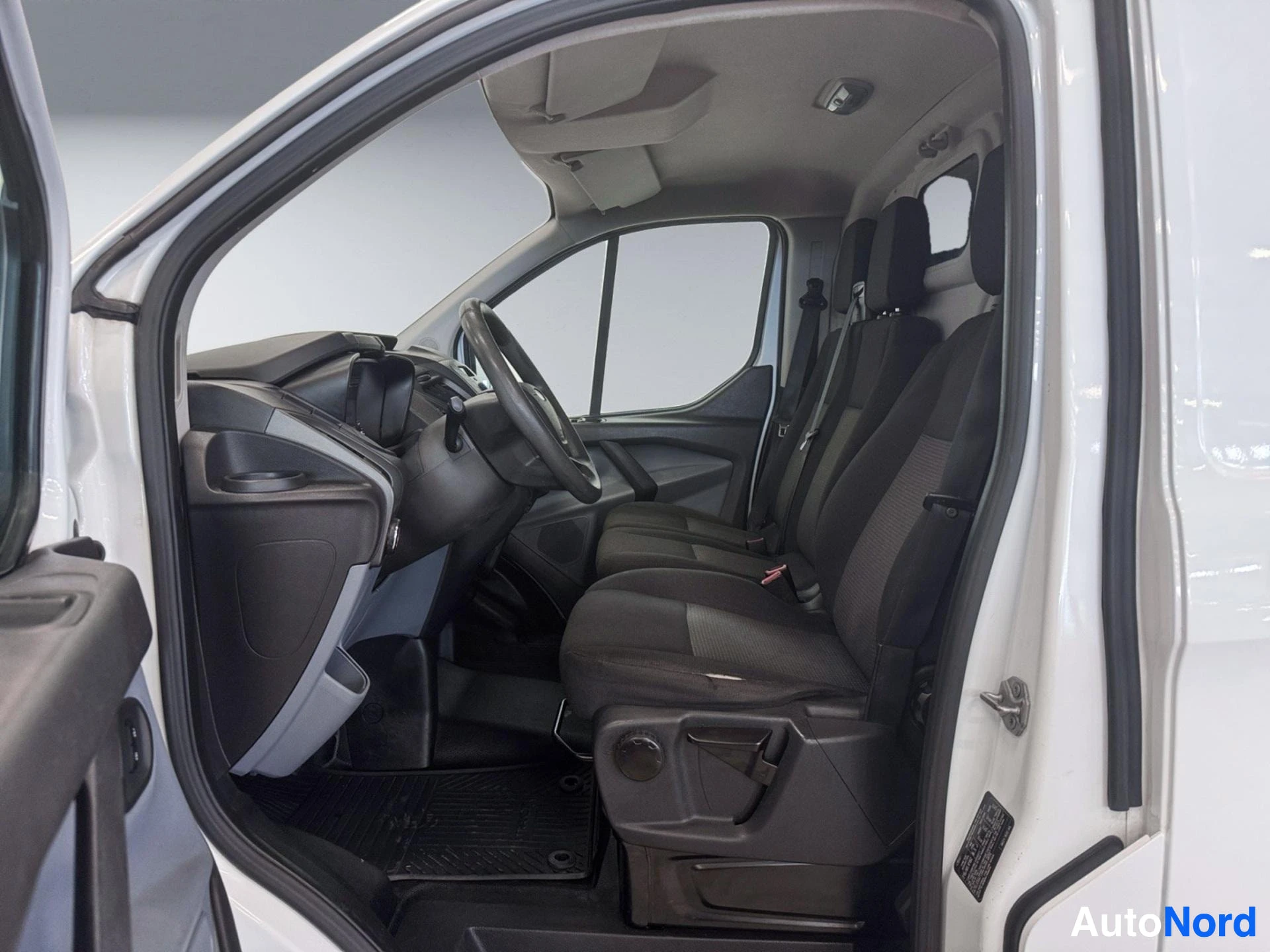 Cab interior with black seats, steering wheel, and windshield view