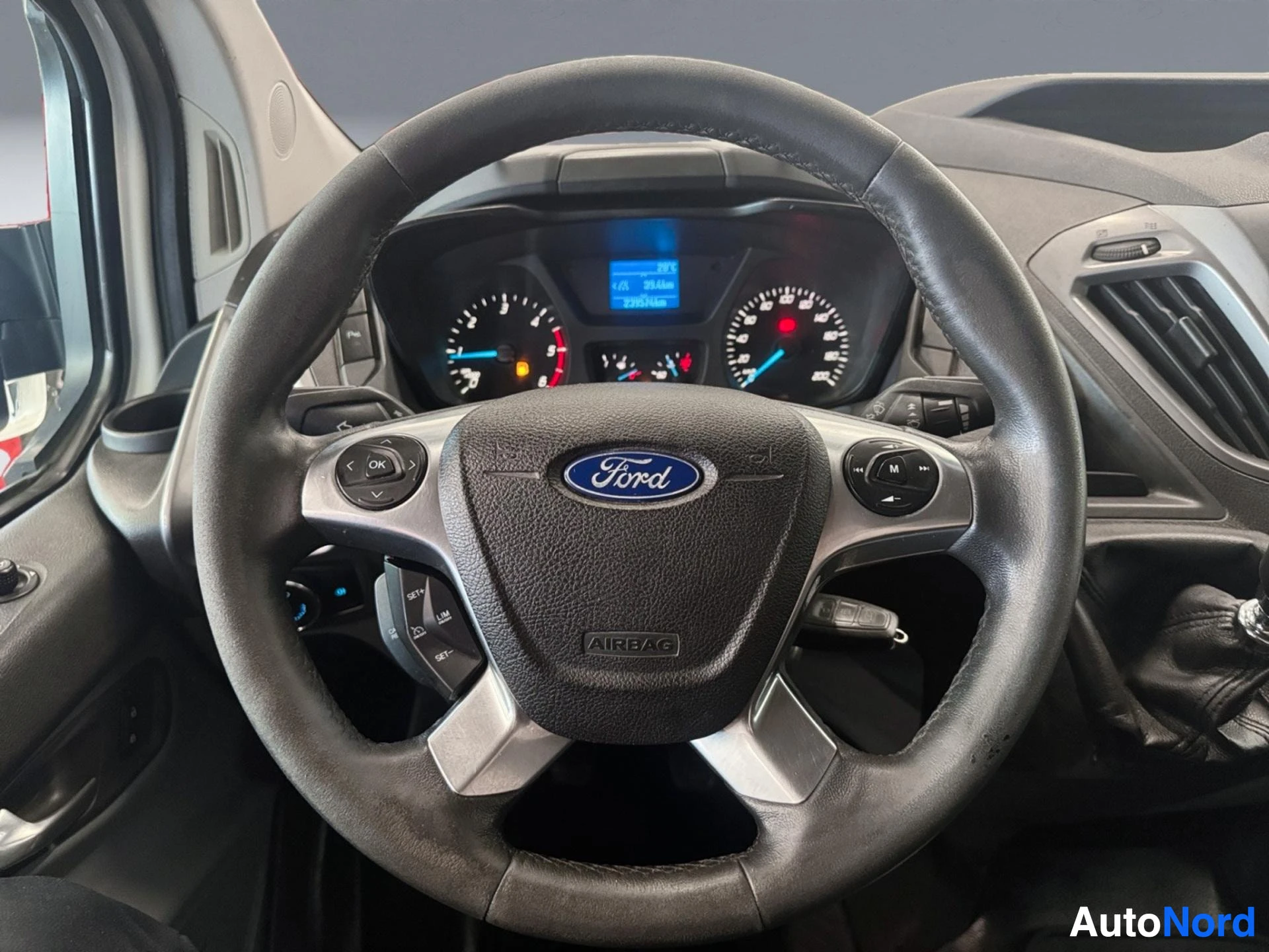 Steering wheel with Ford logo and airbag, dashboard instruments visible behind