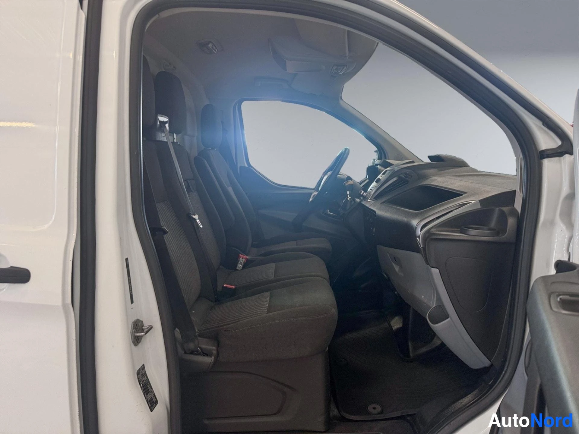 Open driver door view of van interior with black seats and steering wheel visible