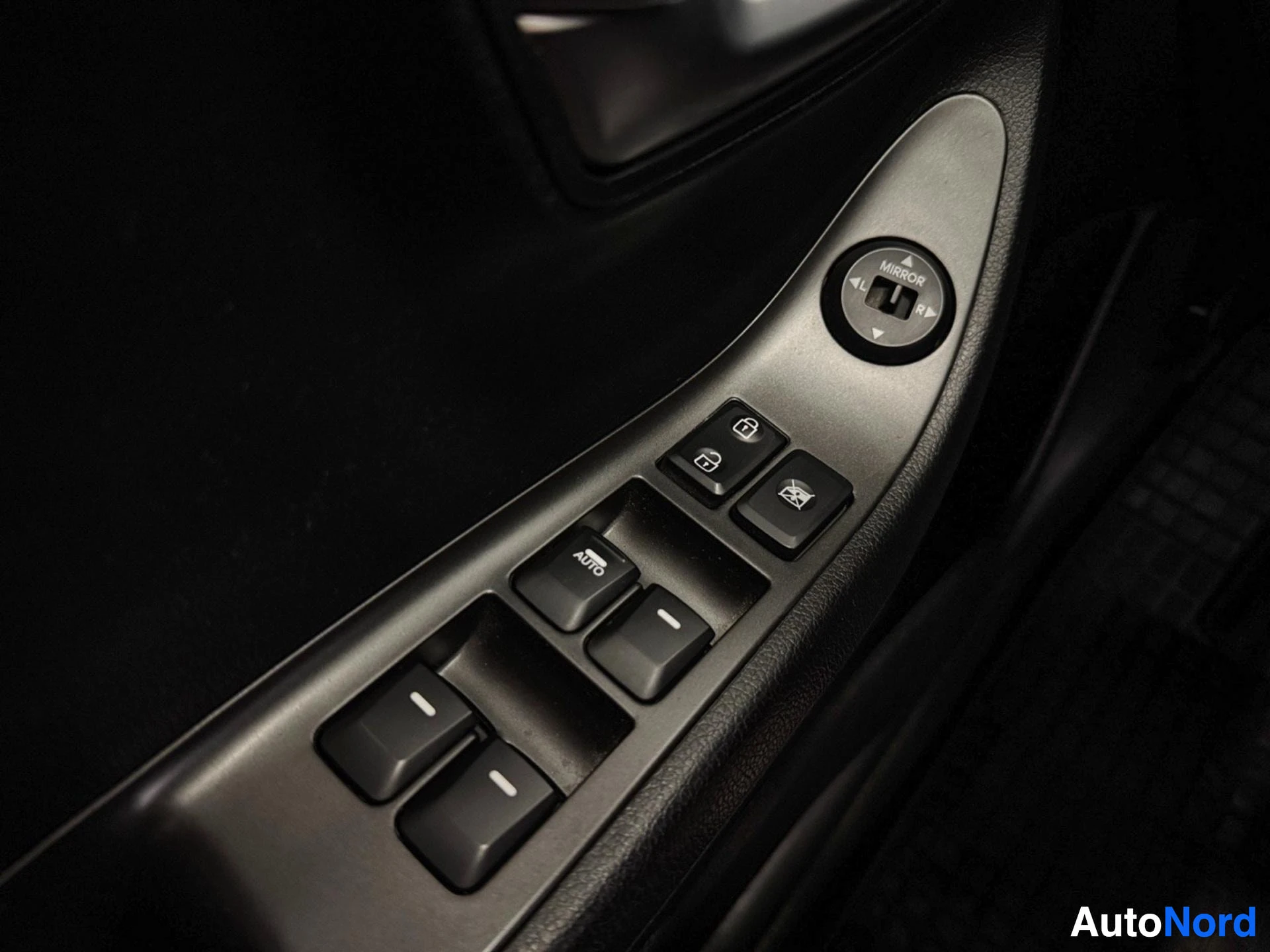 Door panel with power window controls and mirror adjustment buttons on driver side