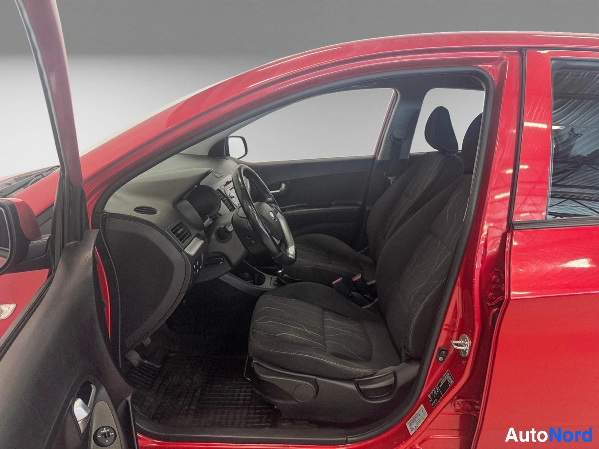 Red Kia Picanto interior with black seats, steering wheel and dashboard visible