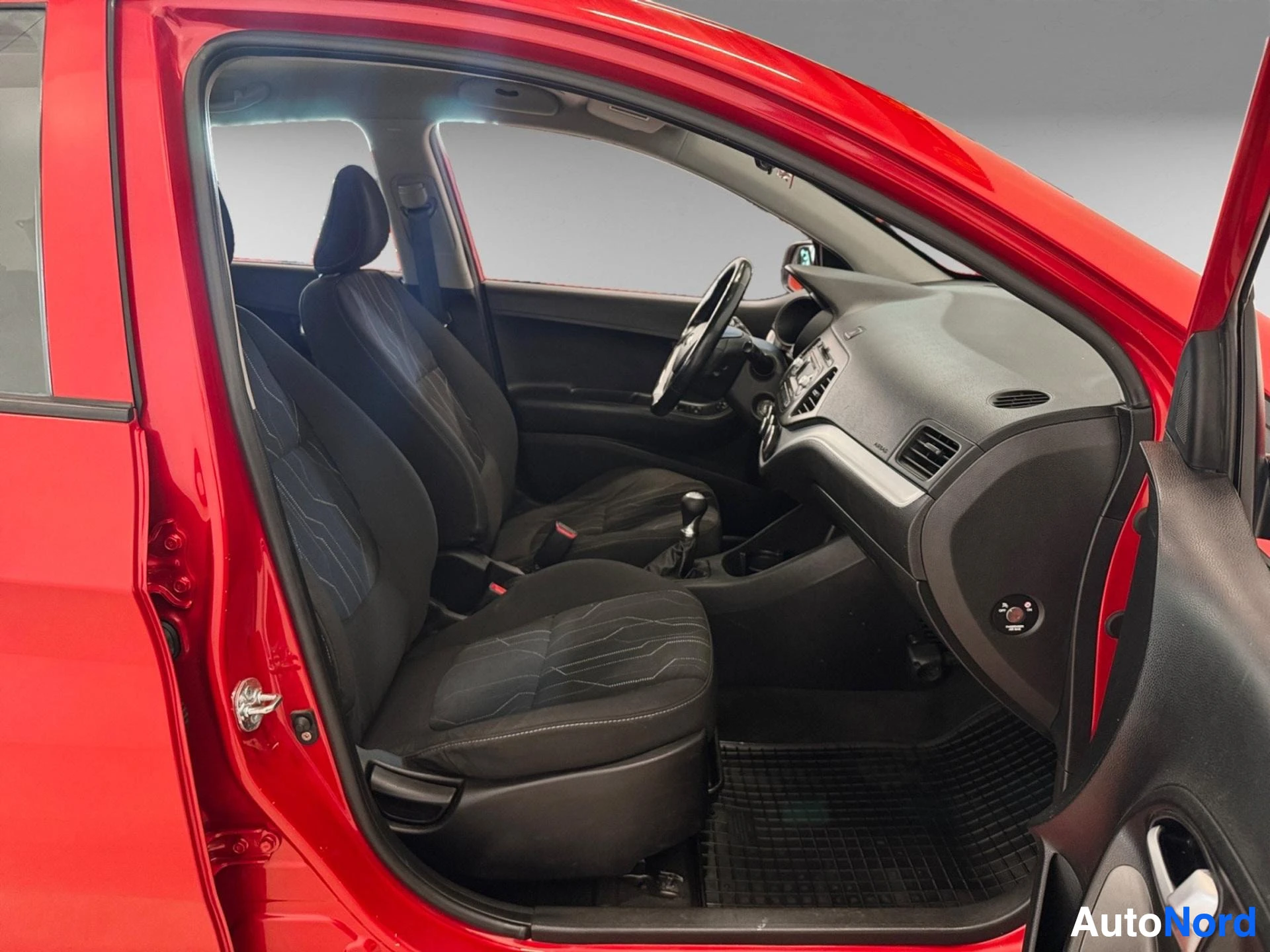Red Kia Picanto driver side interior with black upholstered seats and dashboard