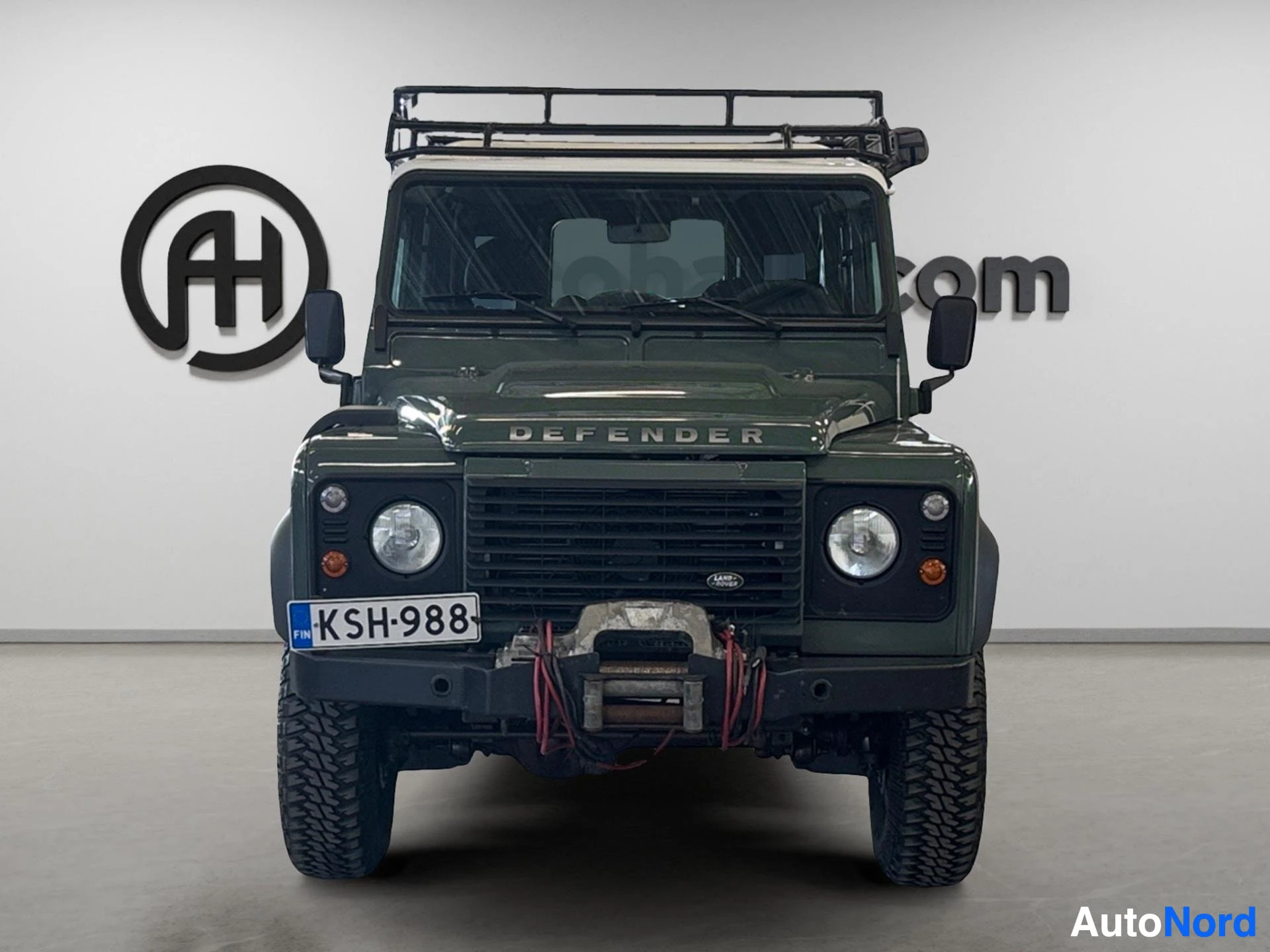 Vihreä Land Rover Defender 110 SW suoraan edestä, roof rack, kuminalusta.