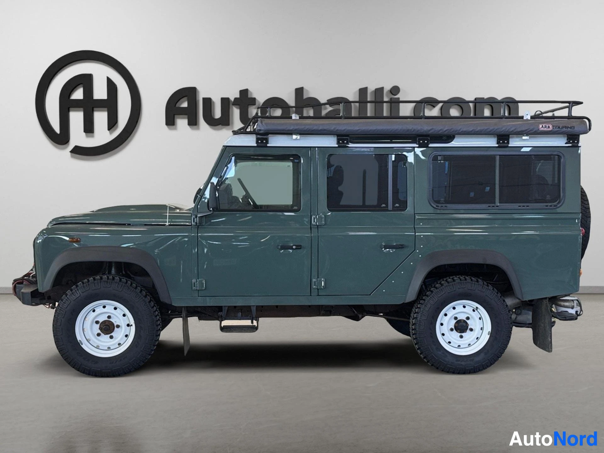 Vihreä Land Rover Defender 110 SW pitkä versio sivusta vasemmalta