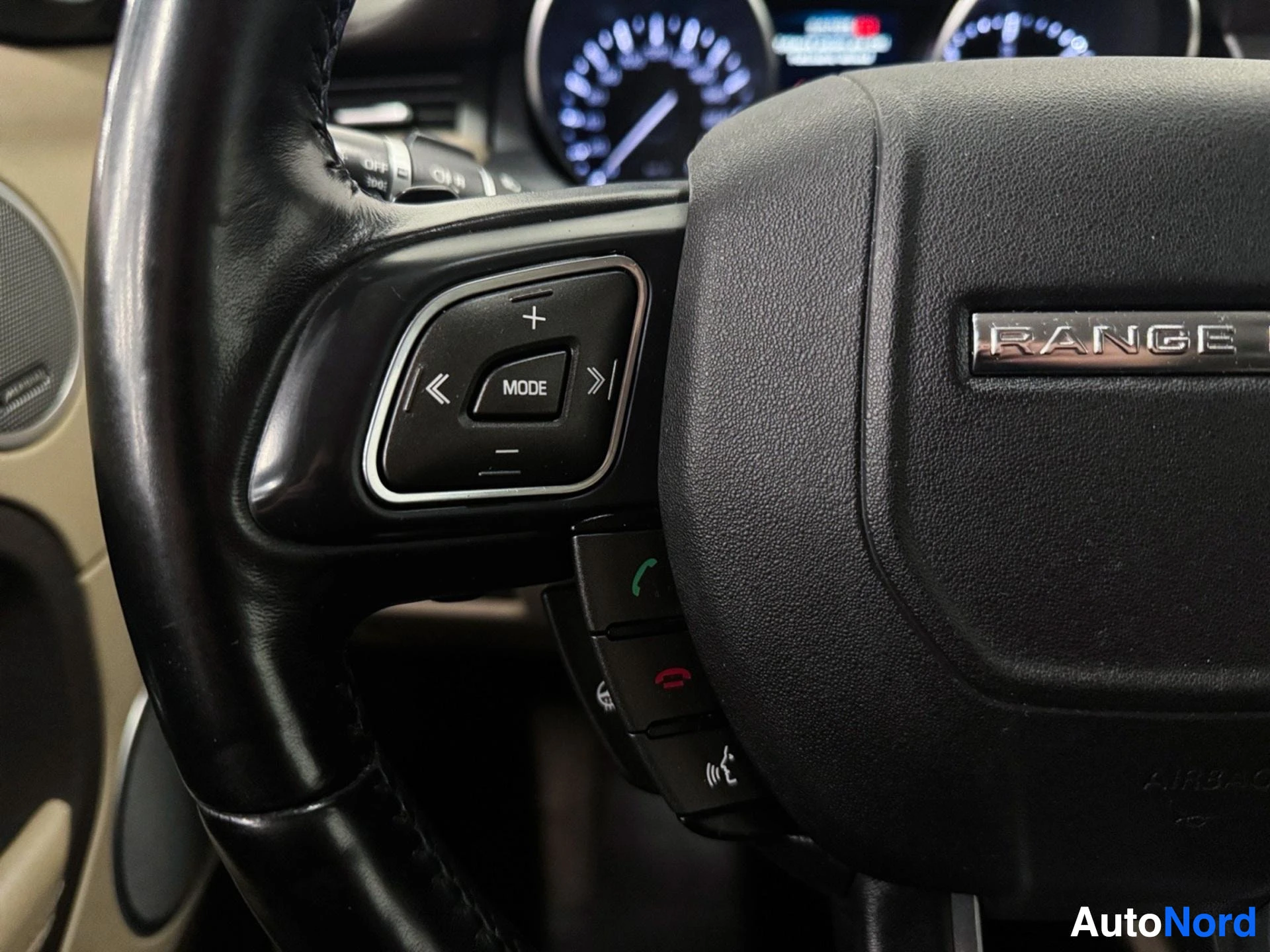 Steering wheel with MODE button and dashboard with illuminated gauges visible