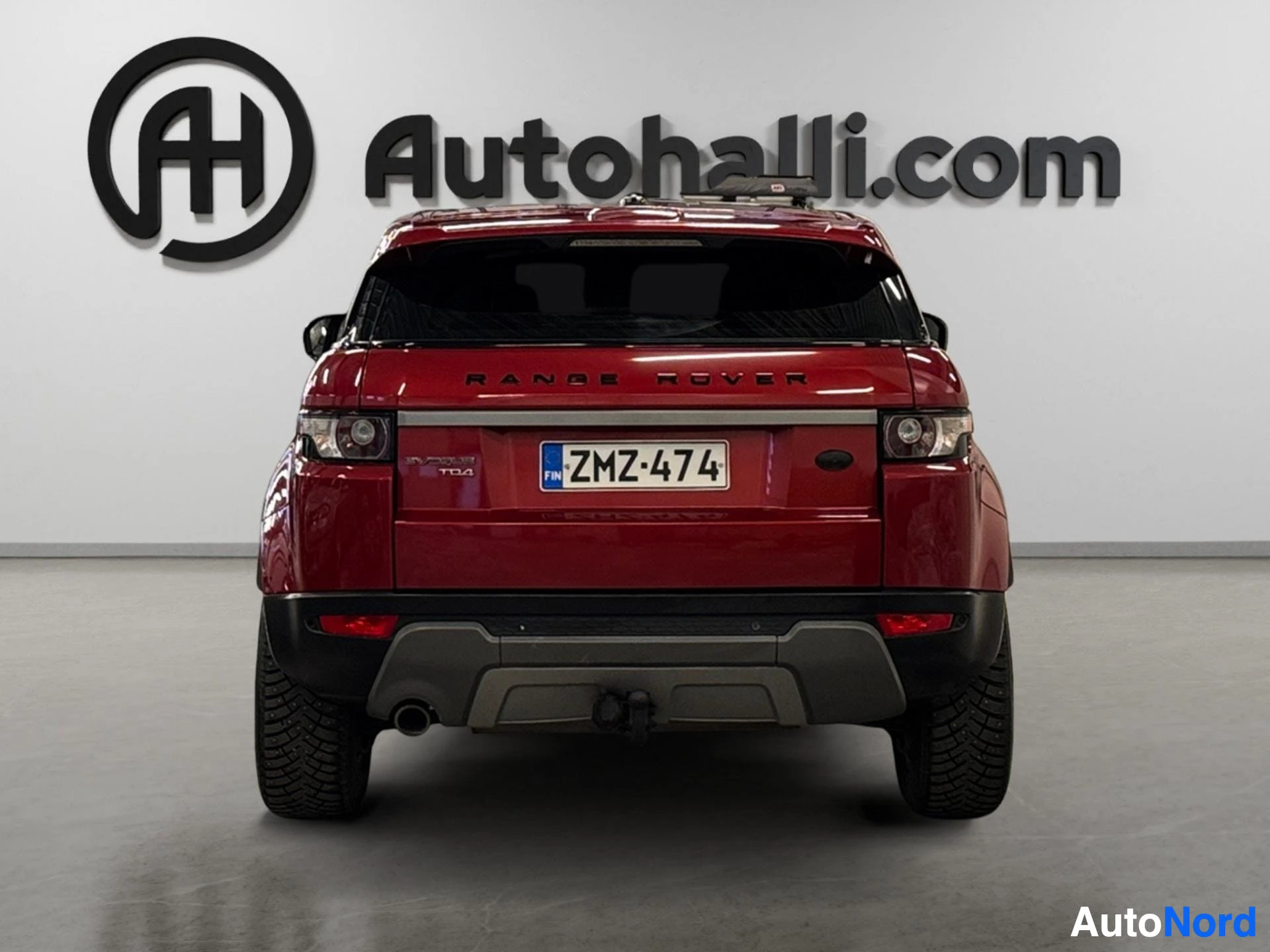Punainen Range Rover Evoque kuvattu suoraan takaa, näkyy rekisterikilvio ja takavalot