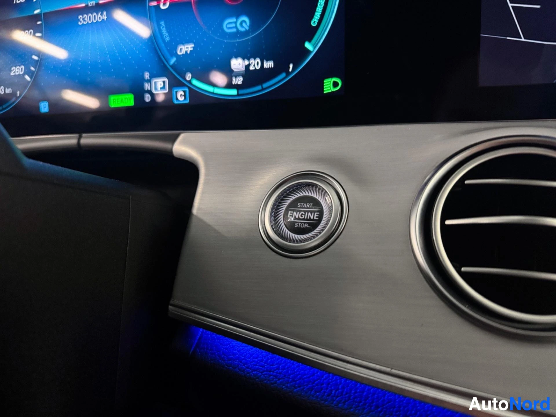 Dashboard with digital instrument cluster, engine start button, and climate control vents.