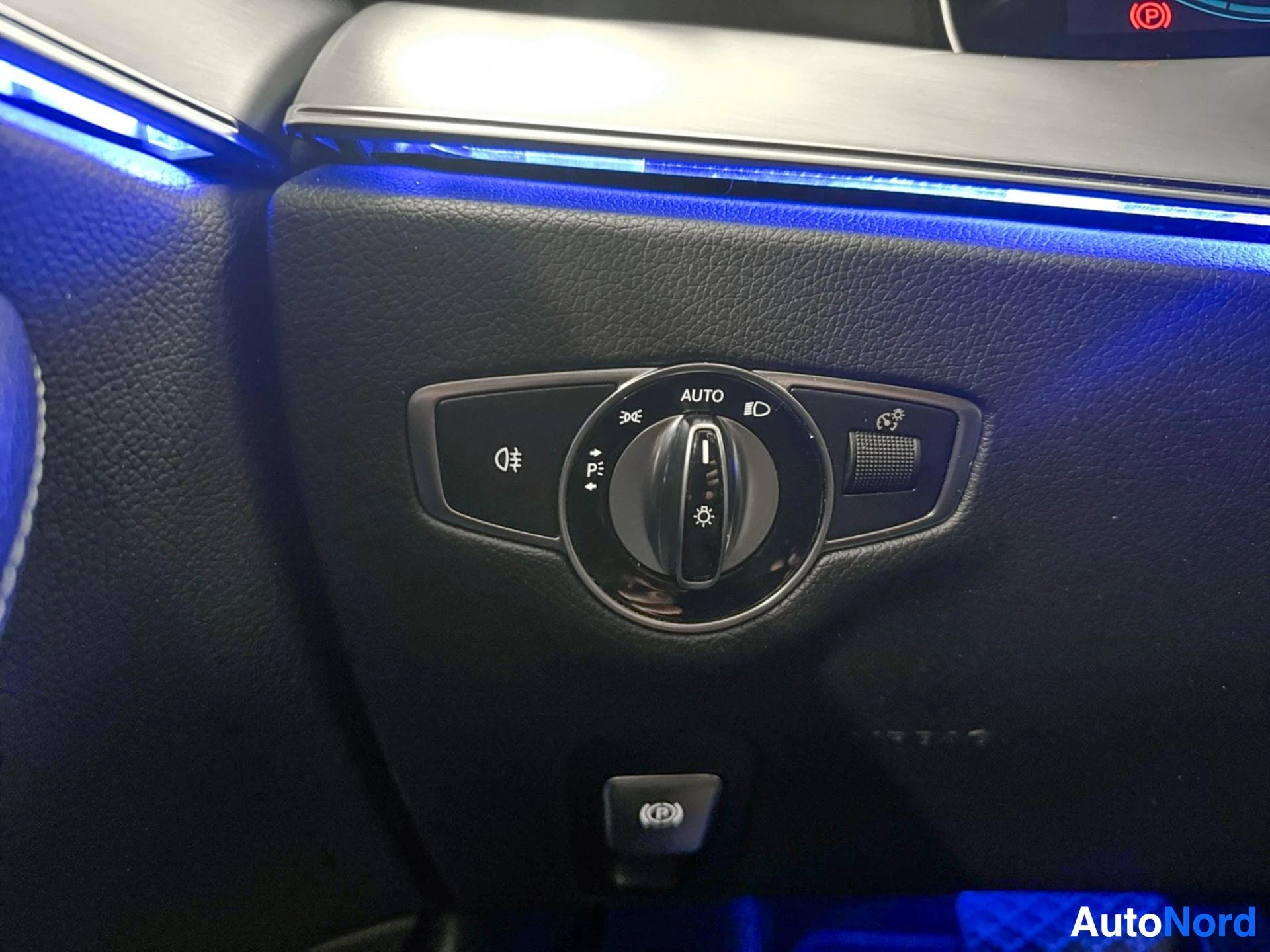 Steering wheel with automatic headlight controls and function buttons in dark leather.