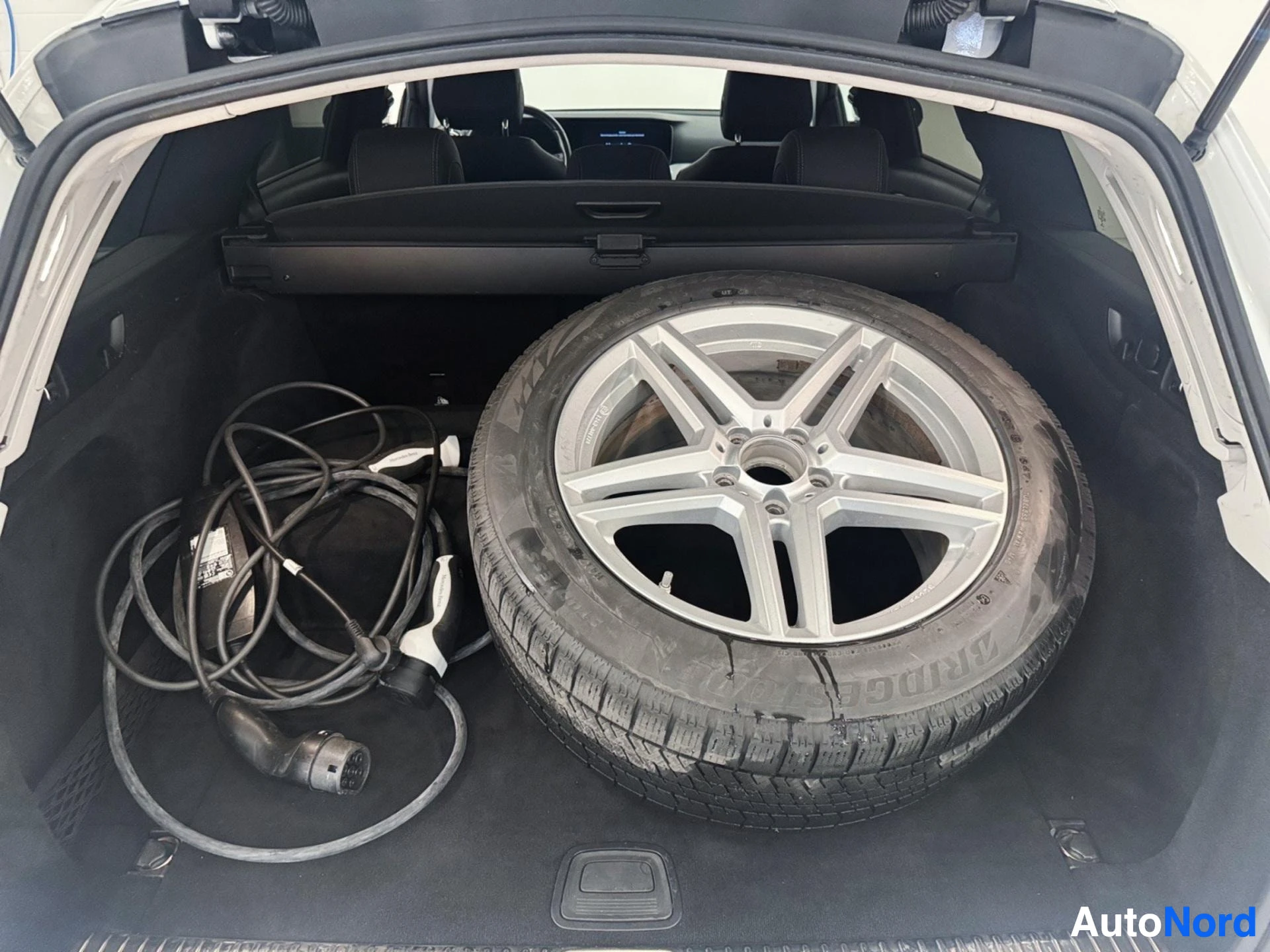 Trunk interior with spare wheel and charging cable for electric vehicle