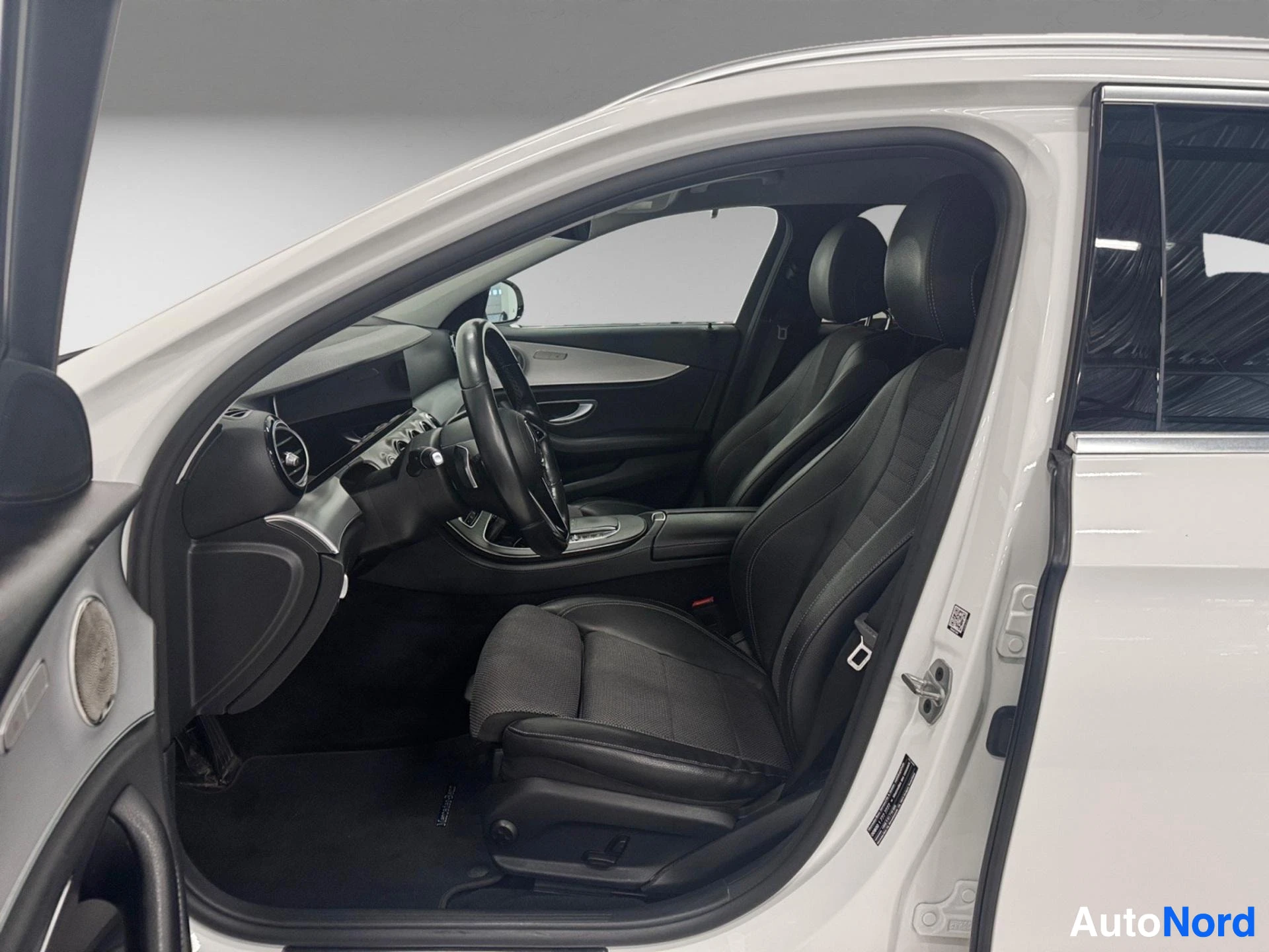 Black leather interior with steering wheel and dashboard visible from open driver side door.