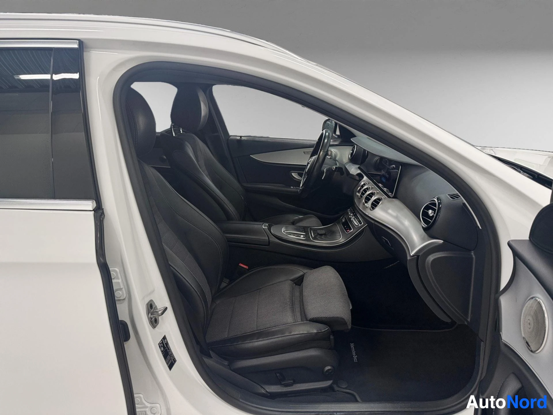 Interior cabin view showing black leather seats, center console and steering wheel from driver side.
