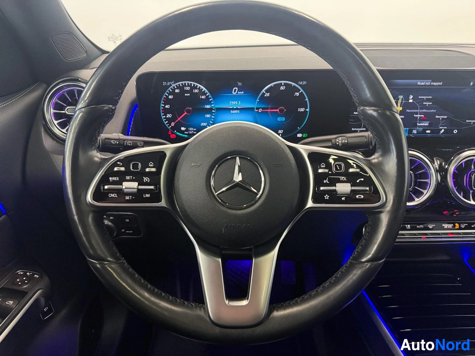 Steering wheel with Mercedes-Benz emblem and multifunction controls, interior dashboard visible.