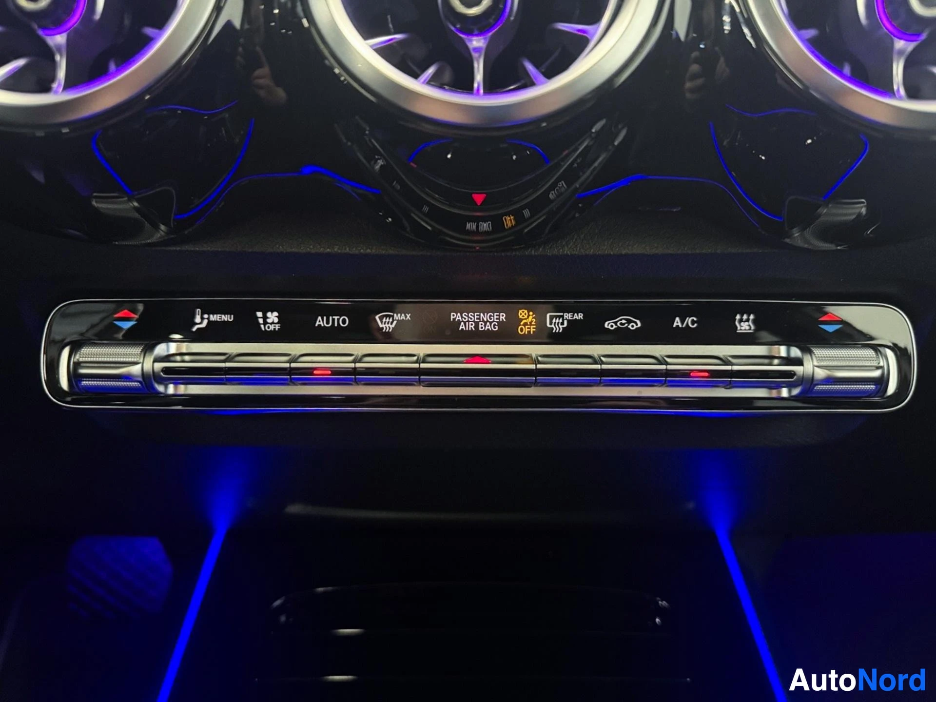 Dashboard control panel with illuminated buttons, climate controls, and blue ambient lighting