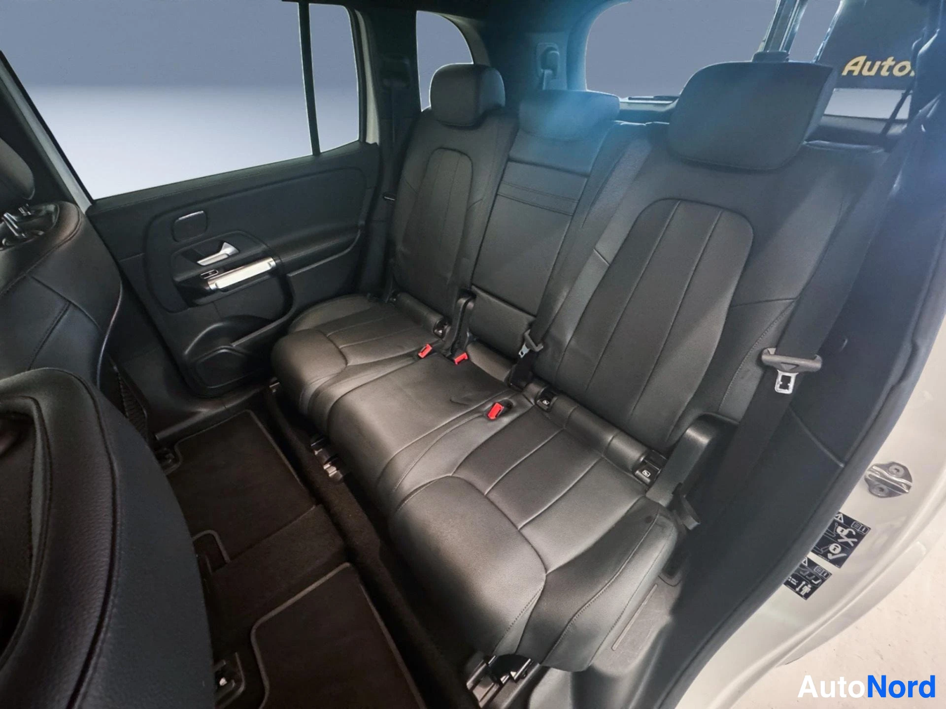 Rear passenger seats with black leather upholstery and safety restraints
