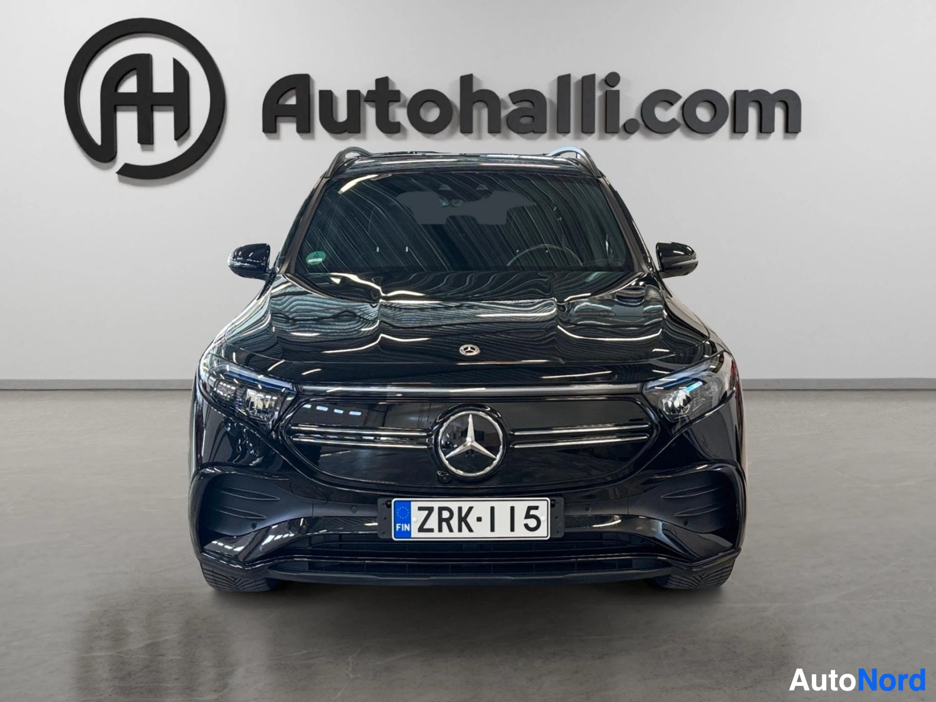 Musta Mercedes-Benz sähköauto edestä nähtynä harmaalla taustalla.
