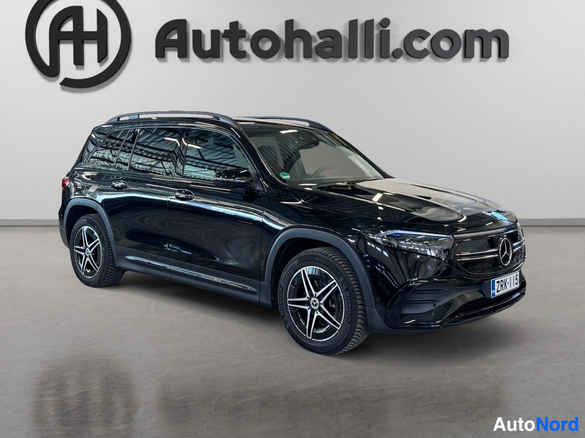 Musta Mercedes-Benz sähköauto sivusta nähtynä harmaalla taustalla.