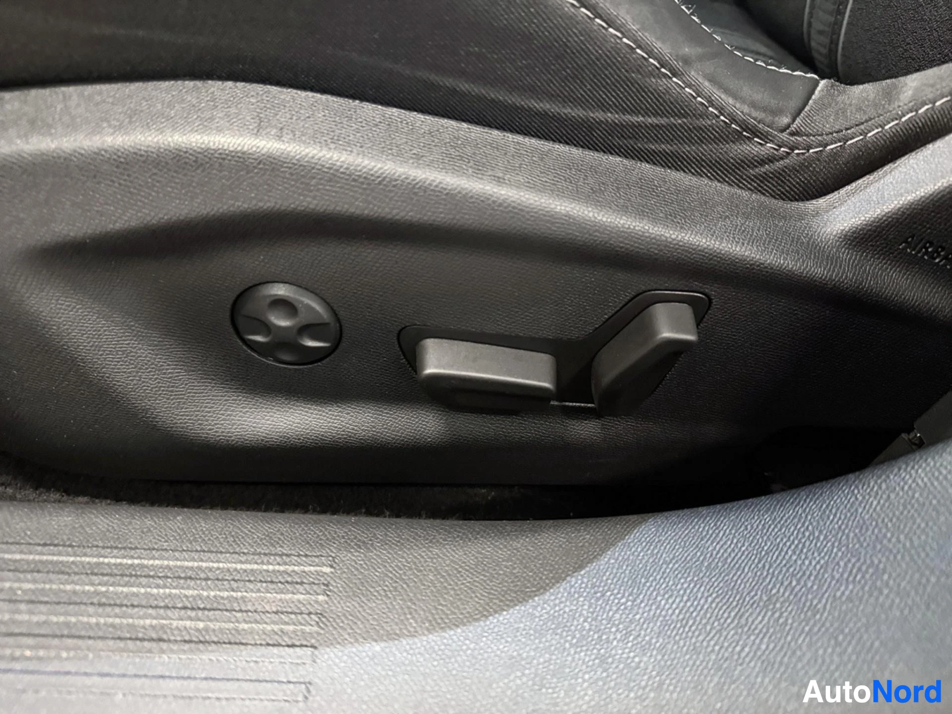 Driver seat adjustment controls on side panel