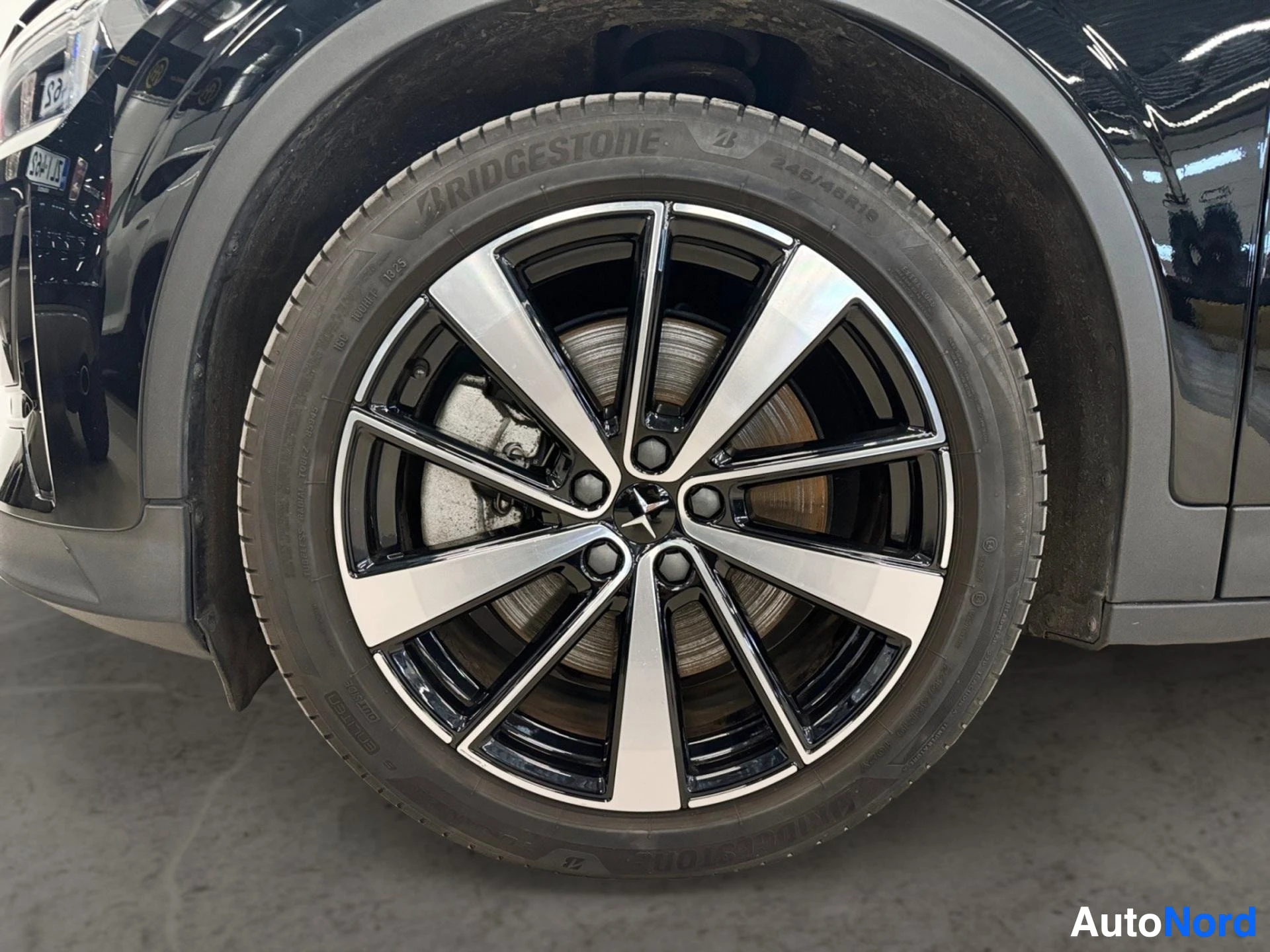 Valkomustemallinen alumiinivanne Bridgestone-renkaalla, auton sivulla