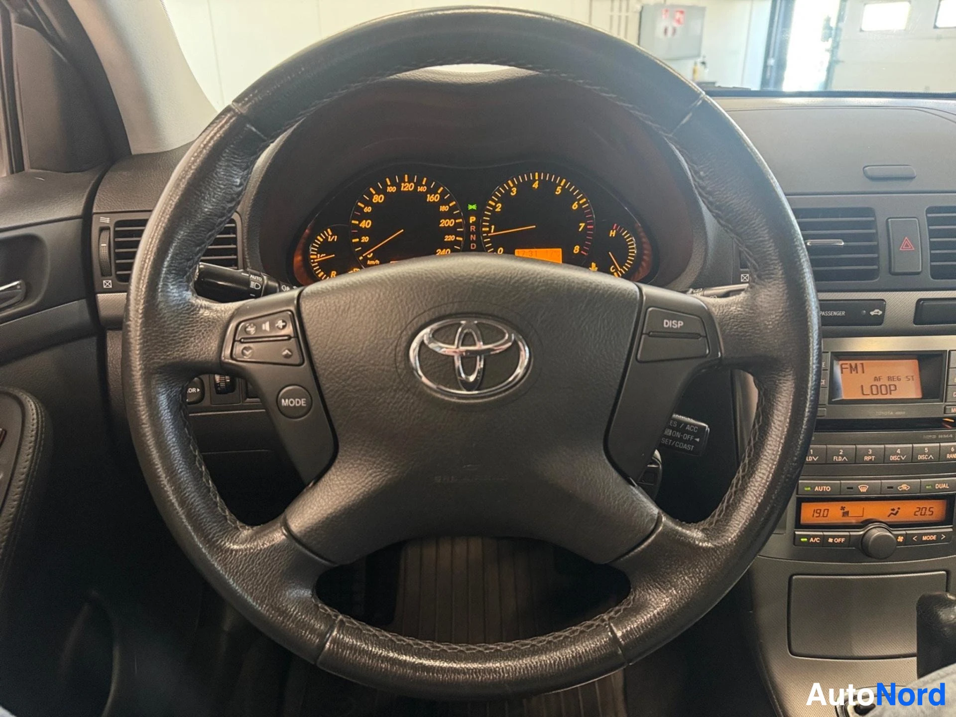 Ohjauspyörän detaljikuva: Toyota-logo ja hallintapainikkeet näkyvissä.