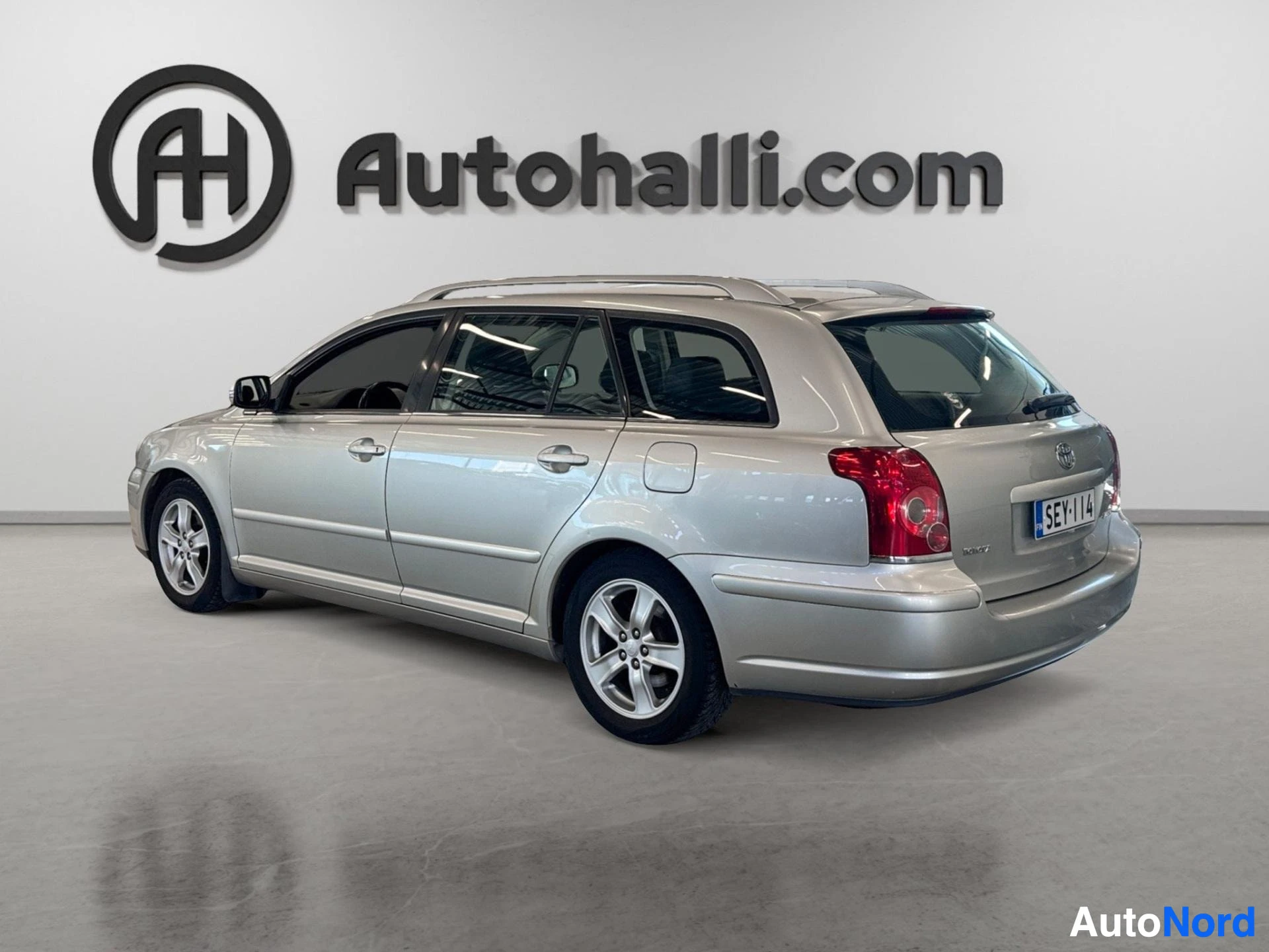 Hopeanvärinen Toyota Avensis farmari takaa vasemmalla kulmalla.