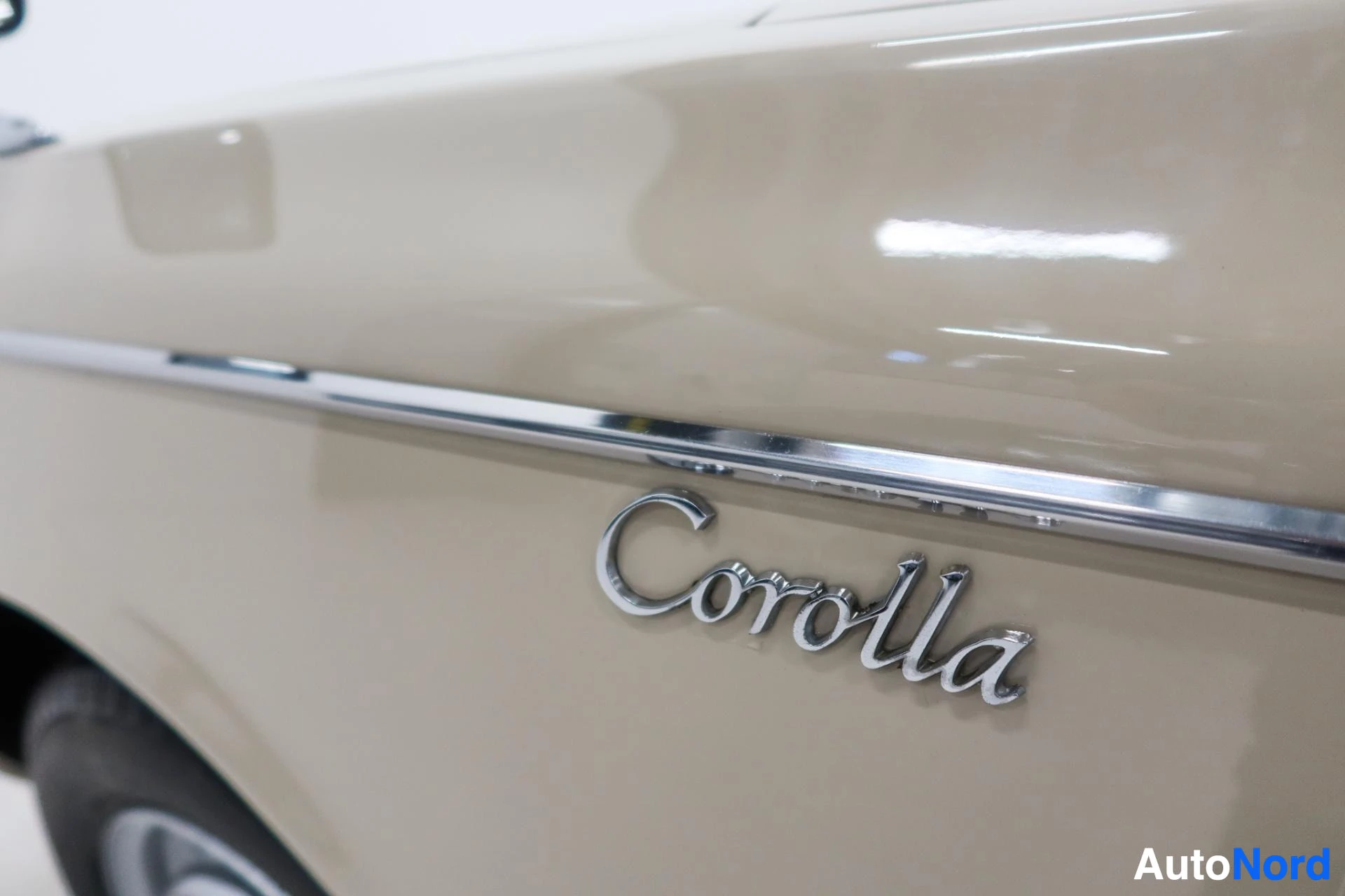 Corolla-merkki vaalealla sivupinnalla kromikehyksineen