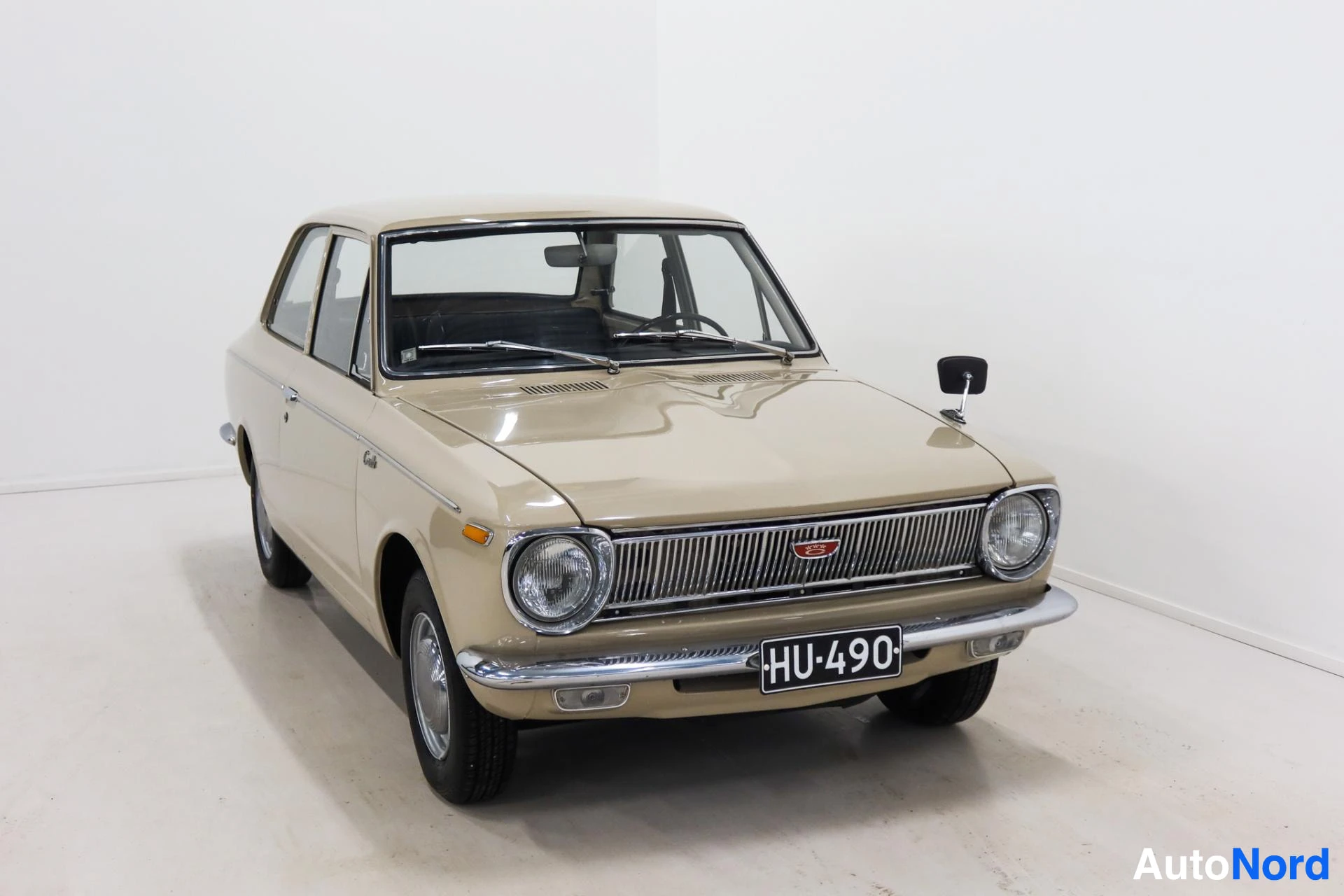 Beige Toyota Corolla front view with round headlights and chrome grille
