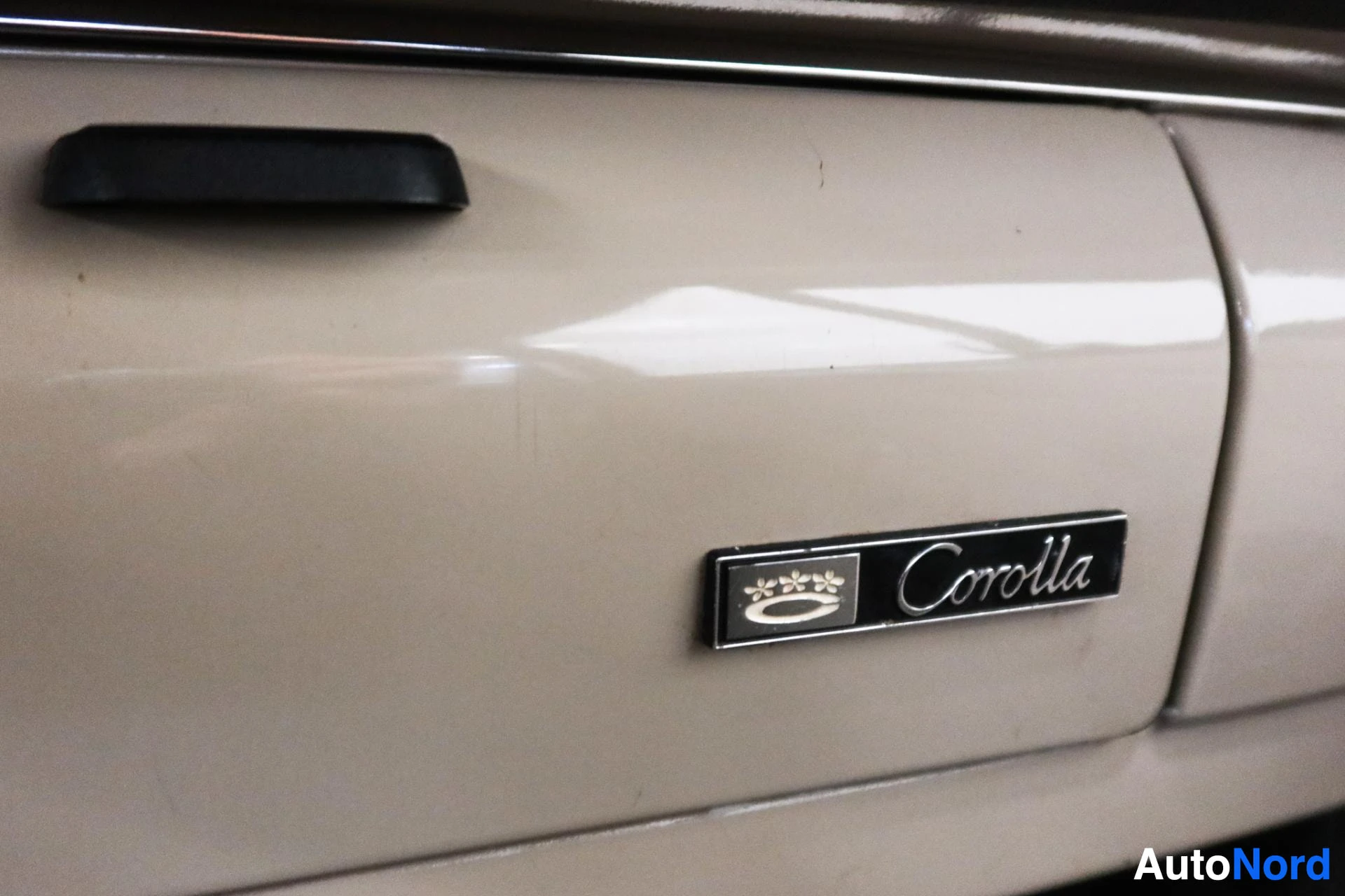 Valkoinen auto sivulta, Corolla-merkki näkyvissä ja musta koristeviiva
