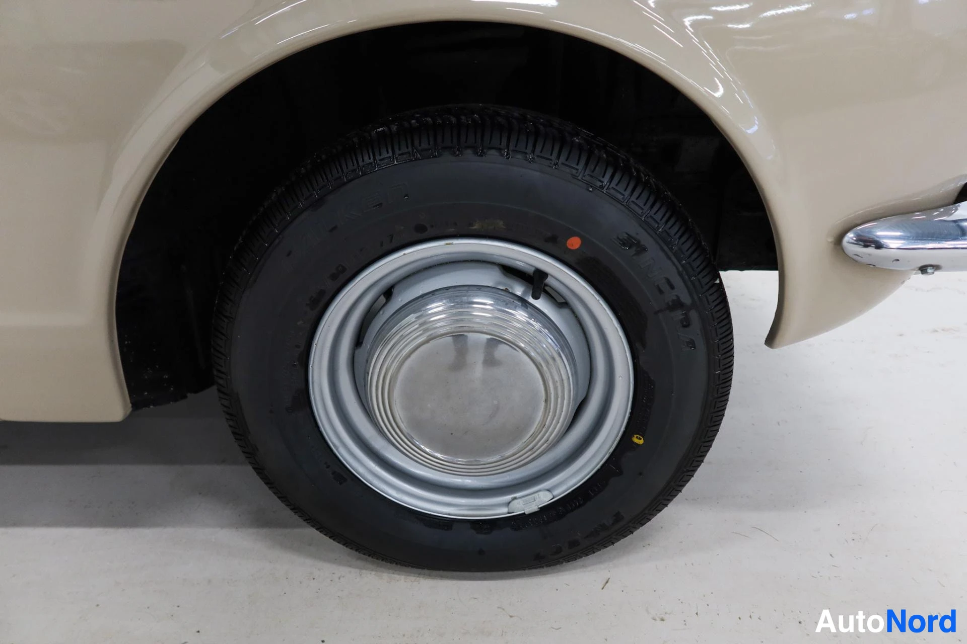 Valkoinen auto, pyörä mustalla renkaalla ja kromivannella, sivusta