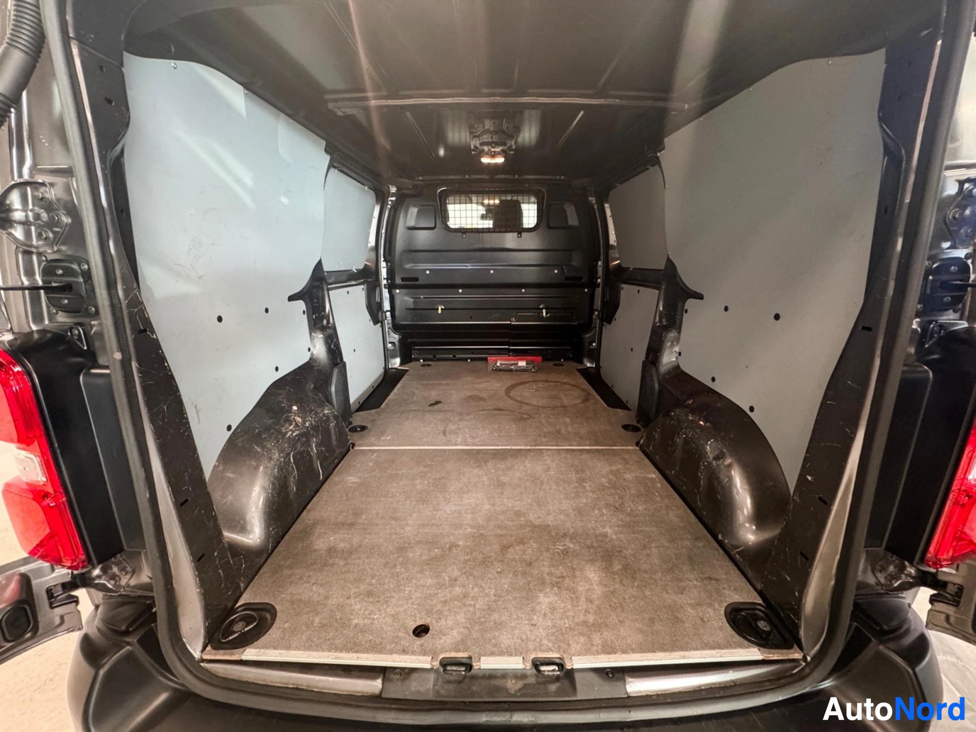 Cargo van interior rear view with brown carpeted floor and white panels