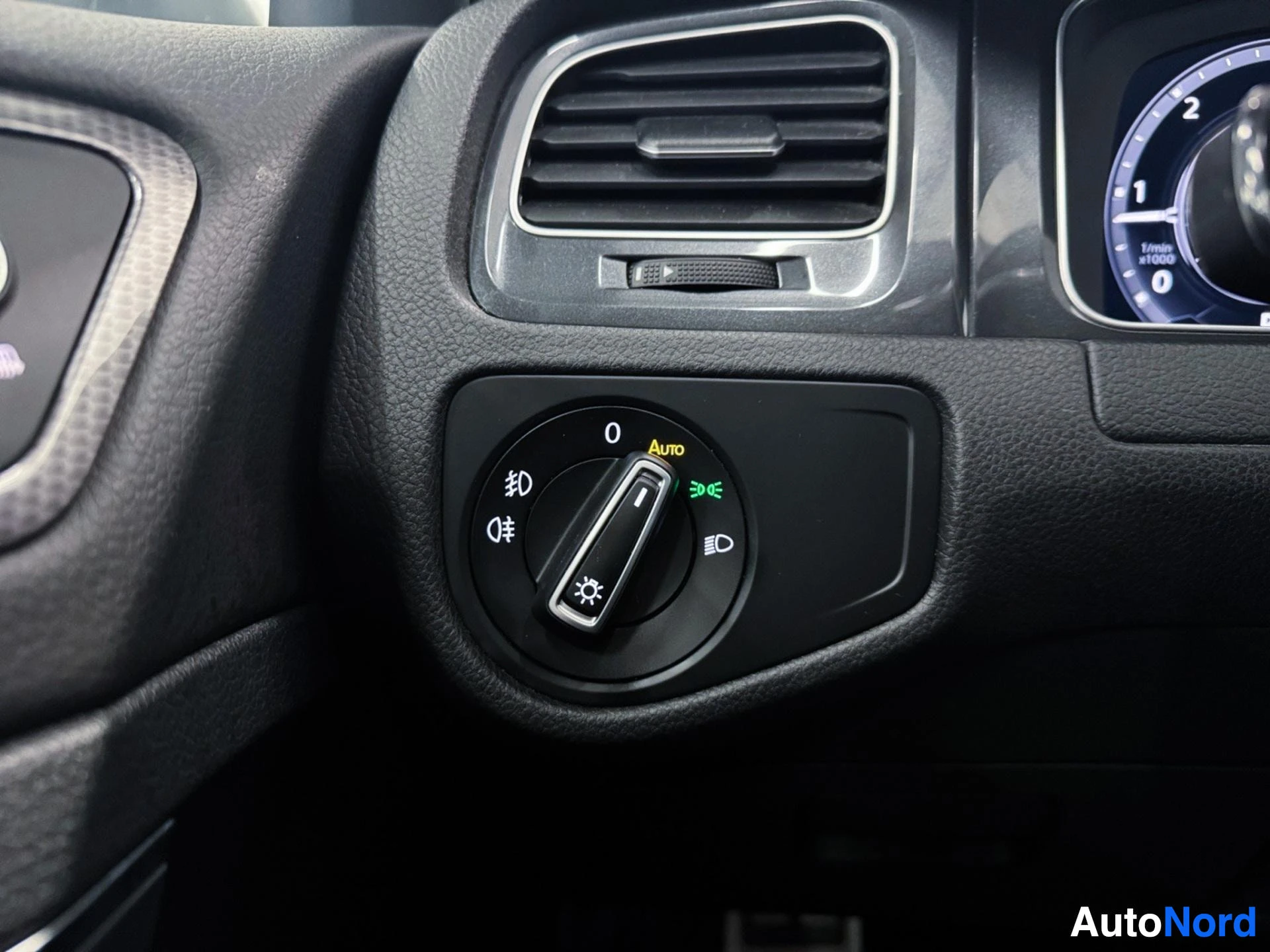 Headlight control dial with AUTO setting and air vent above dashboard.