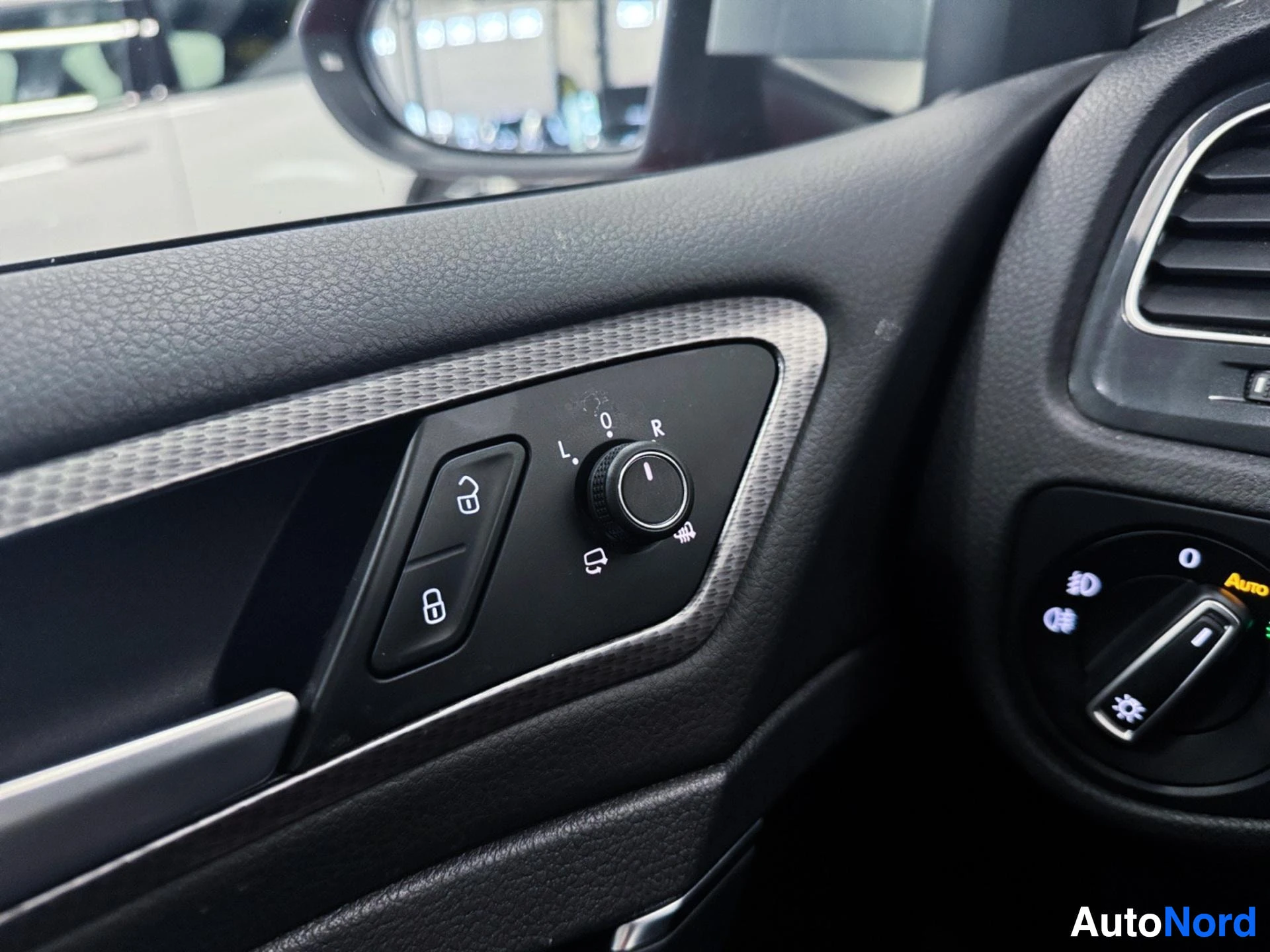 Driver door panel with window and mirror controls, upholstered in black.