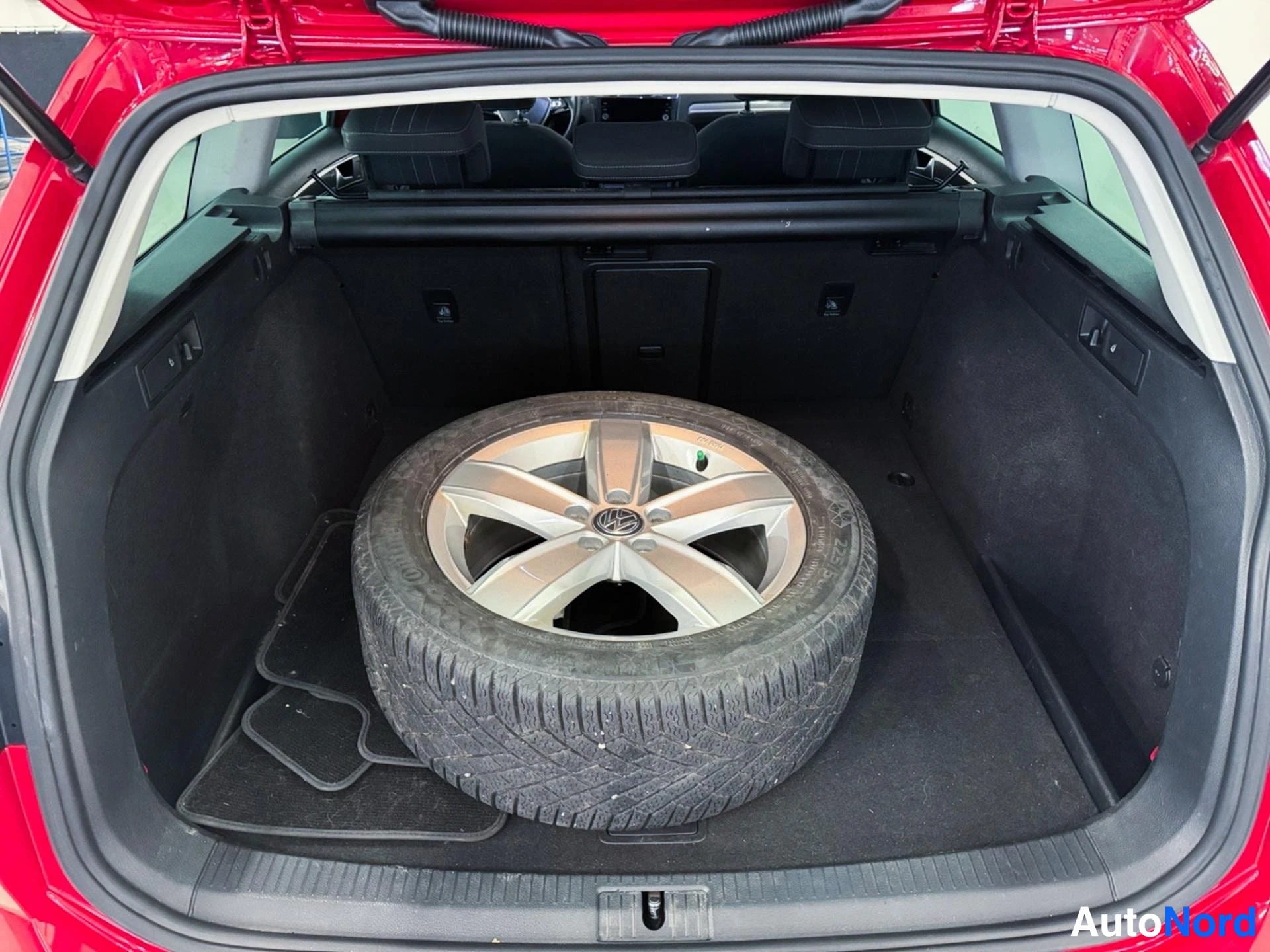 Open trunk showing spare tire on white and black alloy wheel