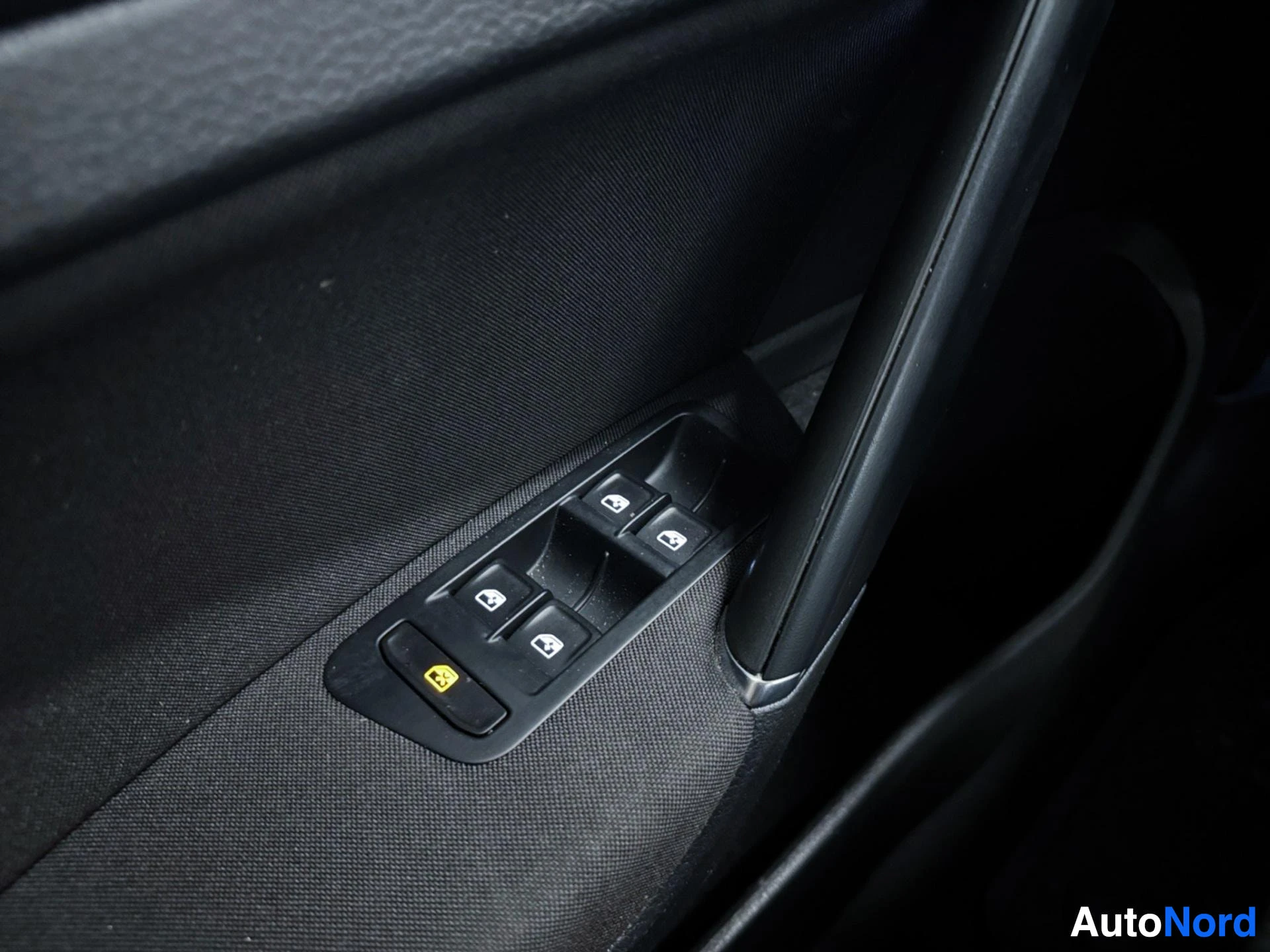 Driver's door panel with electric window control buttons and yellow hazard light button