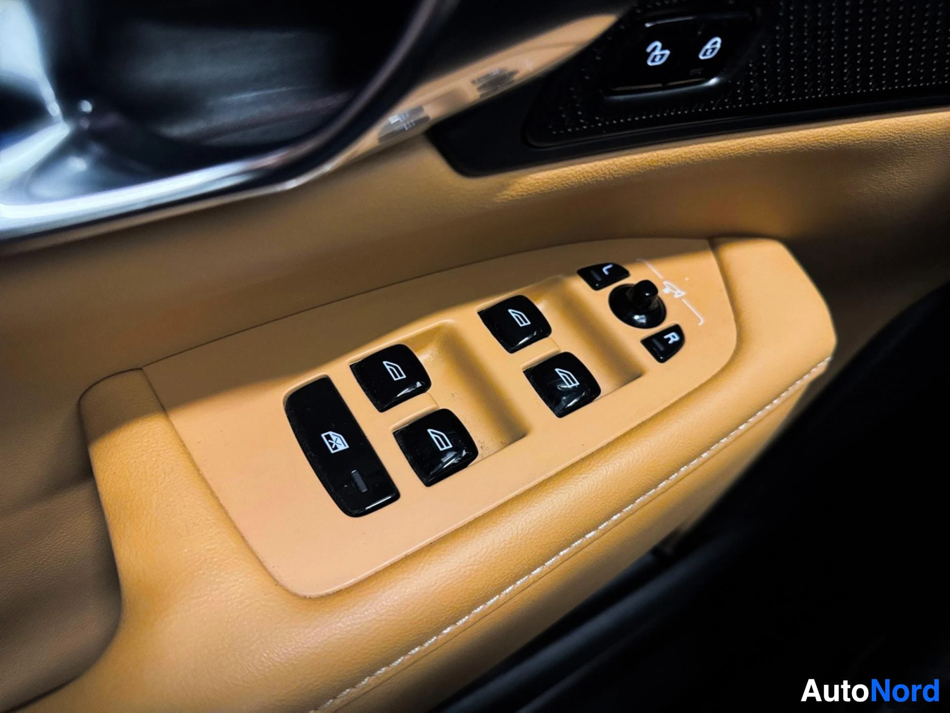 Driver door power window control buttons on tan leather armrest