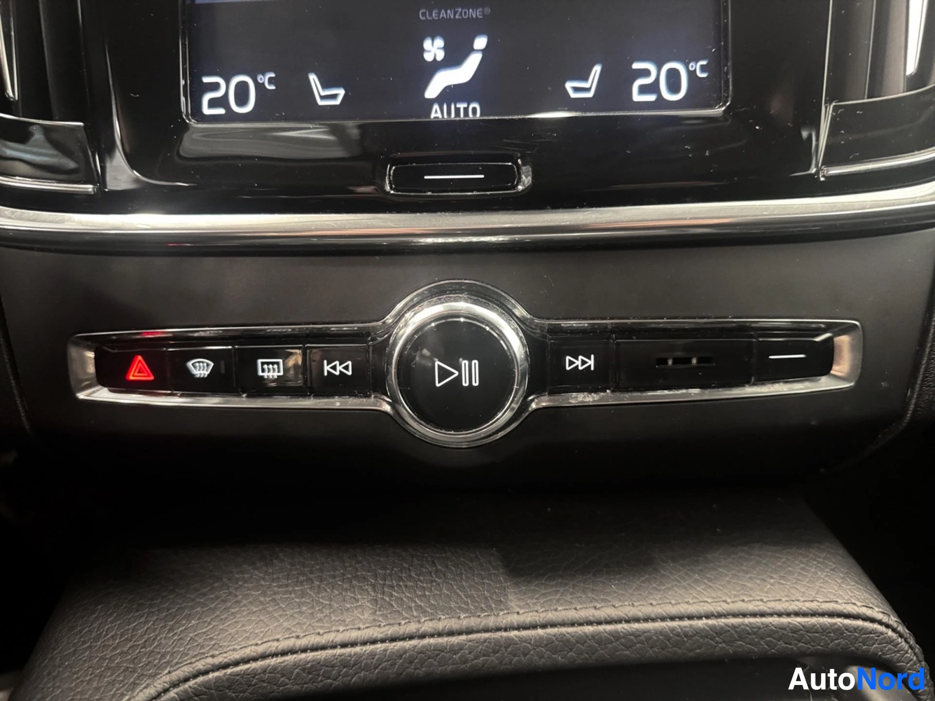 Media control buttons and play pause dial on dashboard below display.