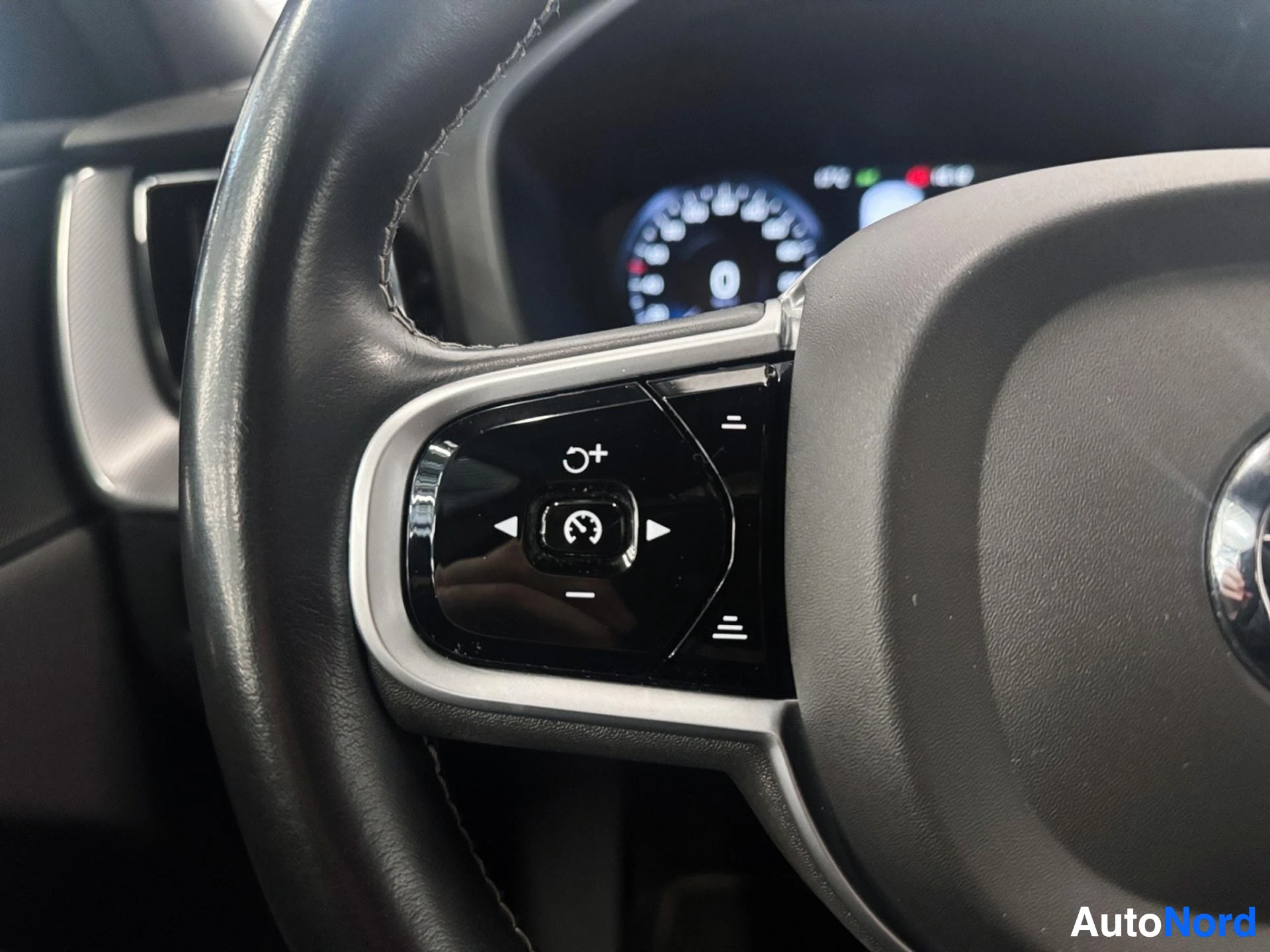 Left side of steering wheel with control buttons and digital display panel.