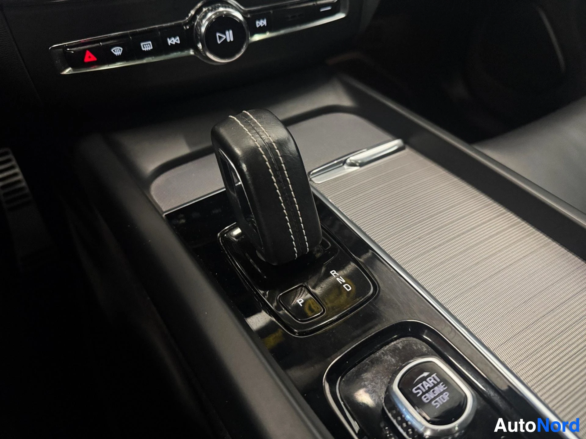 Gear shift lever and start button in center console with media controls above