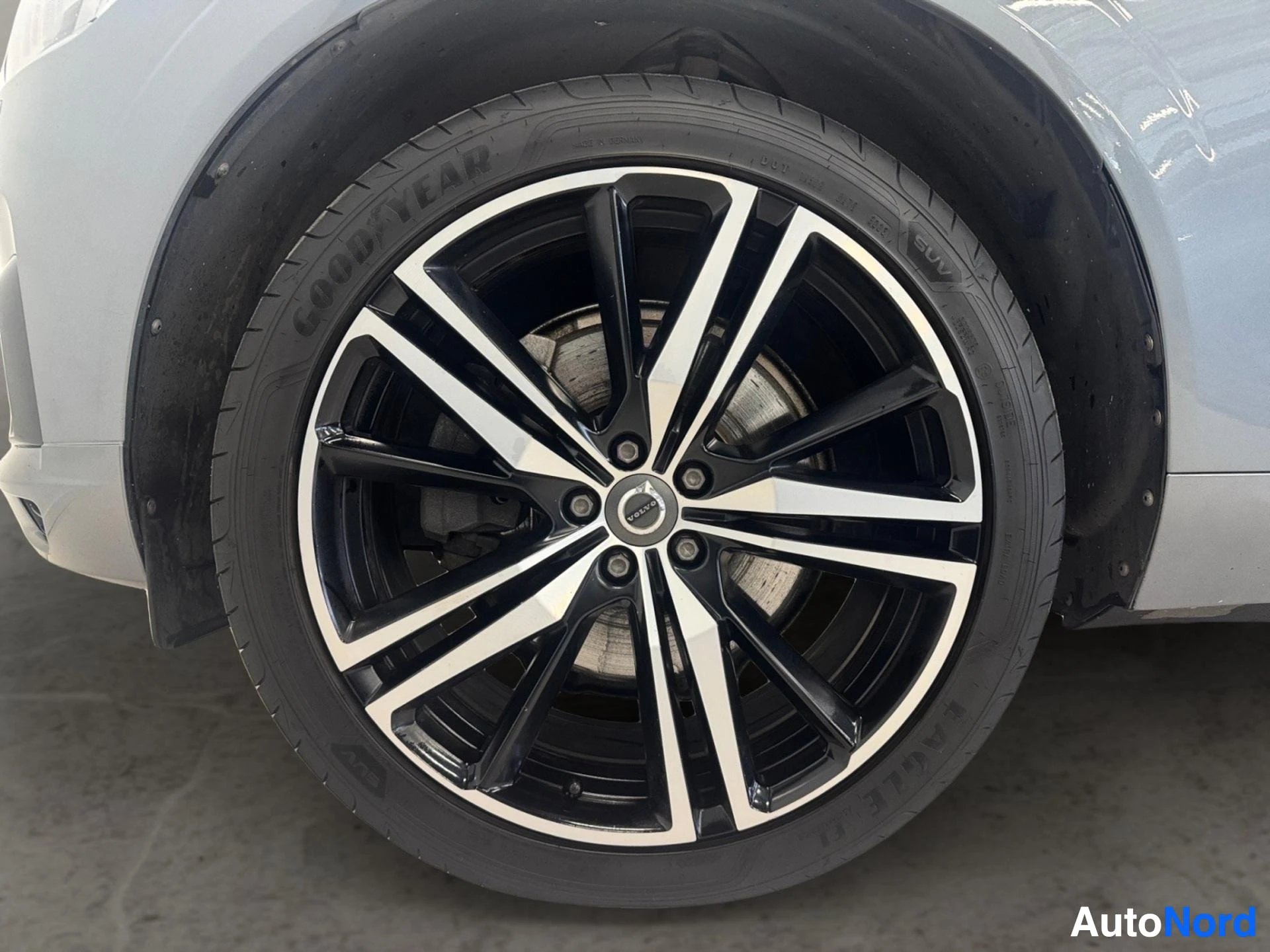 Black and silver alloy wheel with dark tire on white vehicle