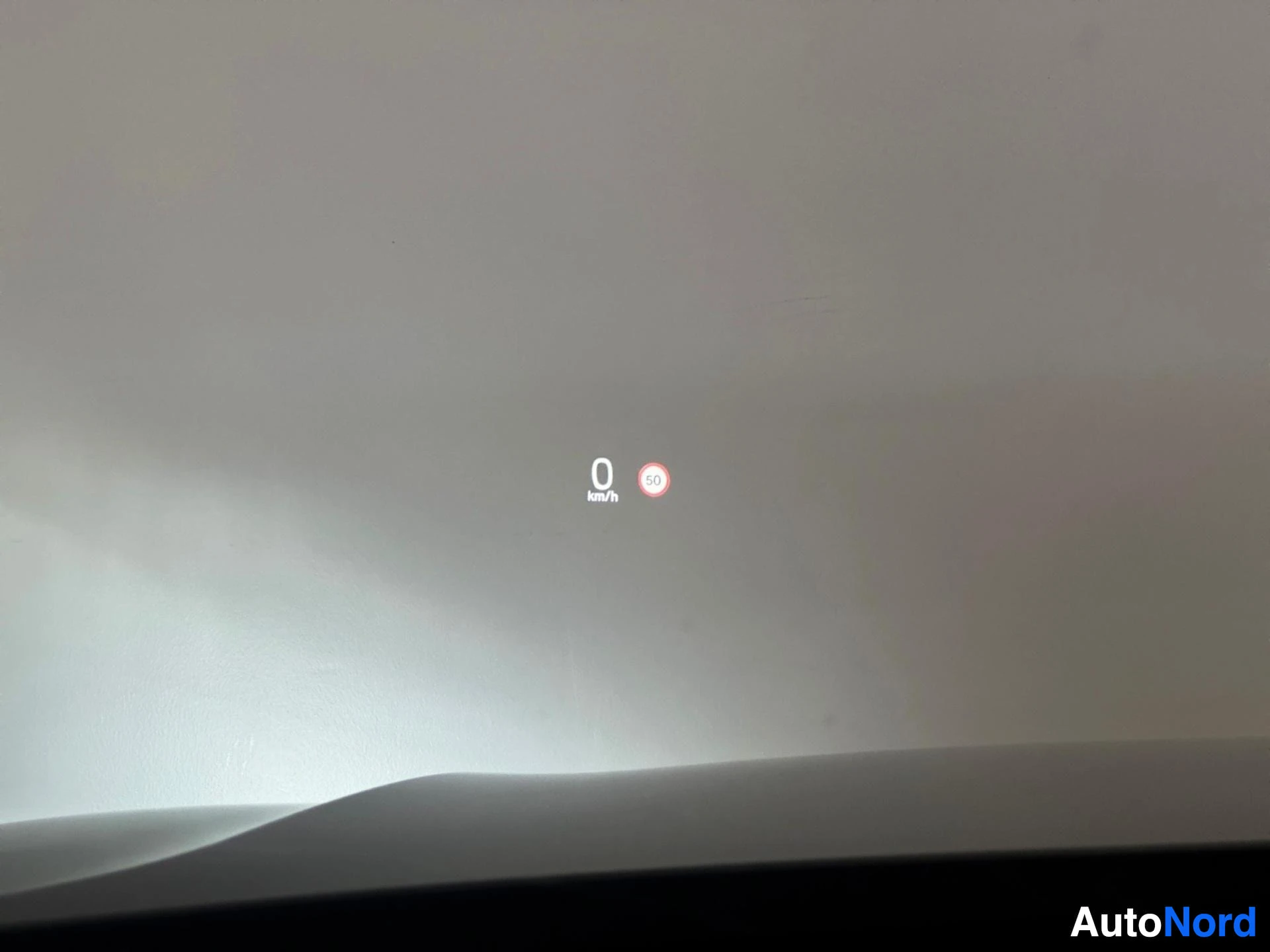 Head-up display showing speed and speed limit indicator on windshield.
