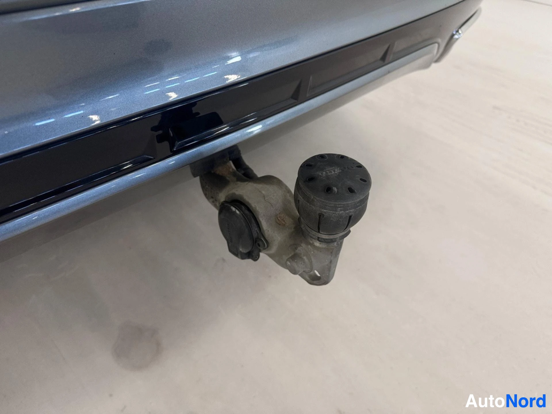 Auton perään kiinnitetty vetokoukun pää sinisen auton kyljellä.