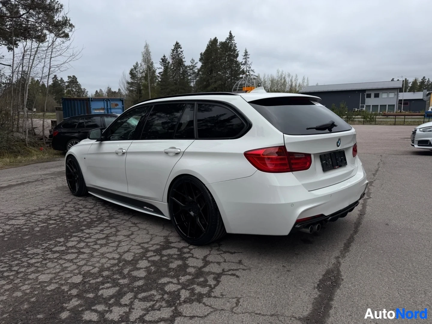 White BMW estate car three-quarter rear view with dark wheels and roof spoiler