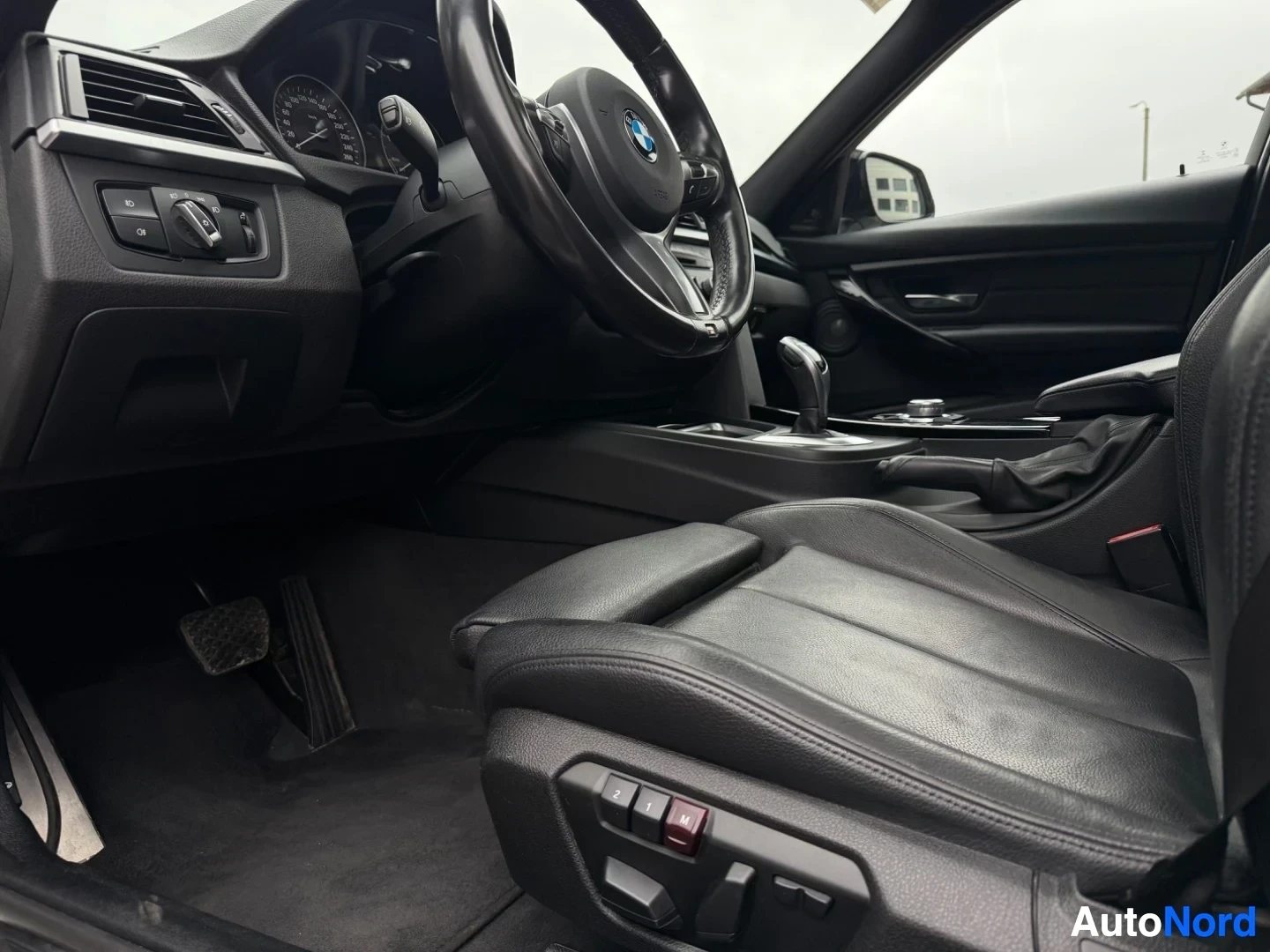 Driver's side interior with leather seat and steering wheel in detail.