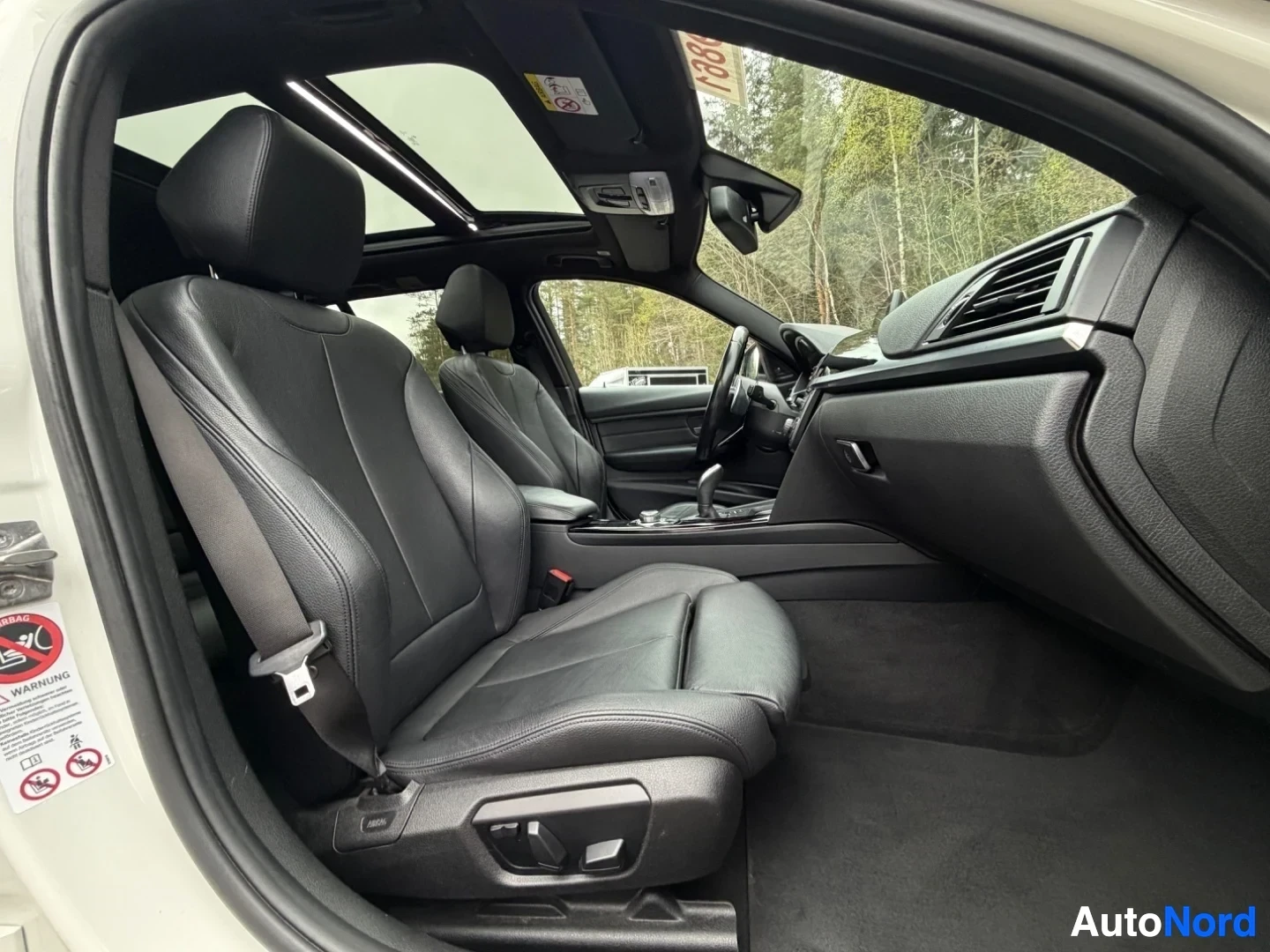 Interior cabin with black leather seats and panoramic sunroof from side view