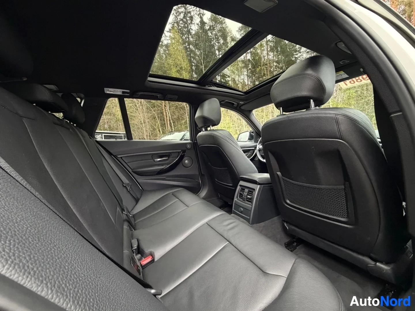 Black leather rear seats with panoramic sunroof and headrests visible.