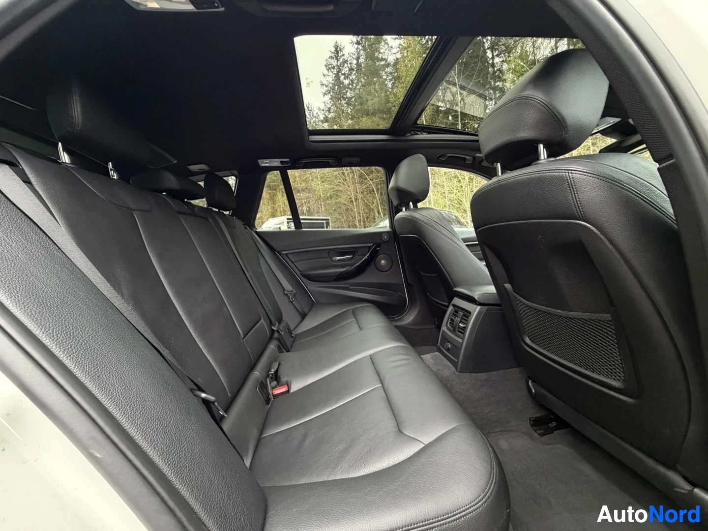 Black leather rear seats with panoramic sunroof and headrest details shown.