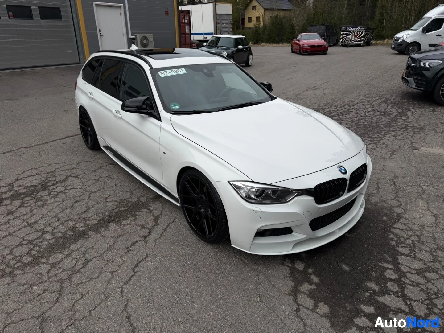 Valkoinen BMW farmari ylhäältä edessä kuvattu, mustat vanteet, parkkipaikalla